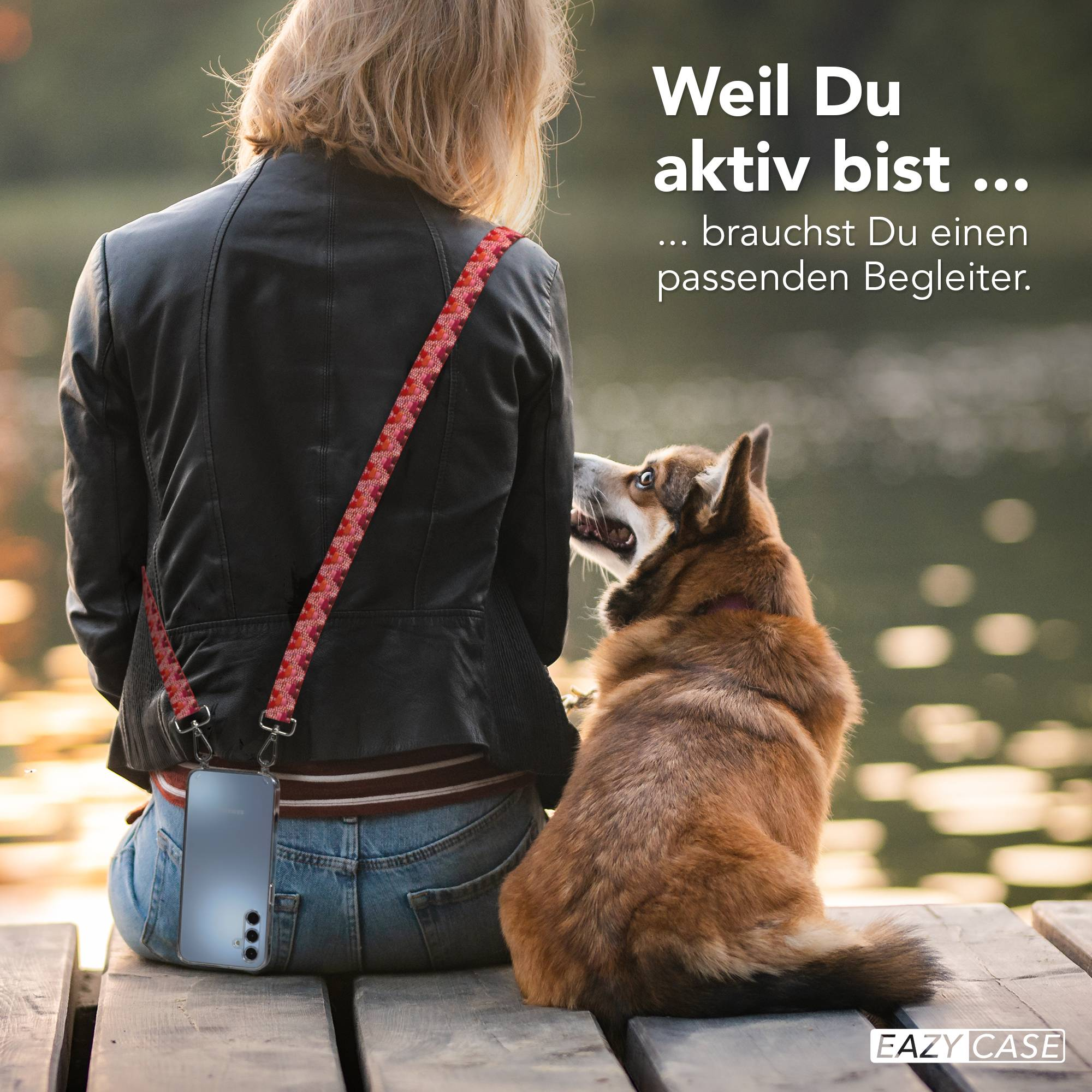 Ein Hund schaut eine Frau an, die auf einer Holzplattform sitzt. Sie hat ein Handy am Gurt.