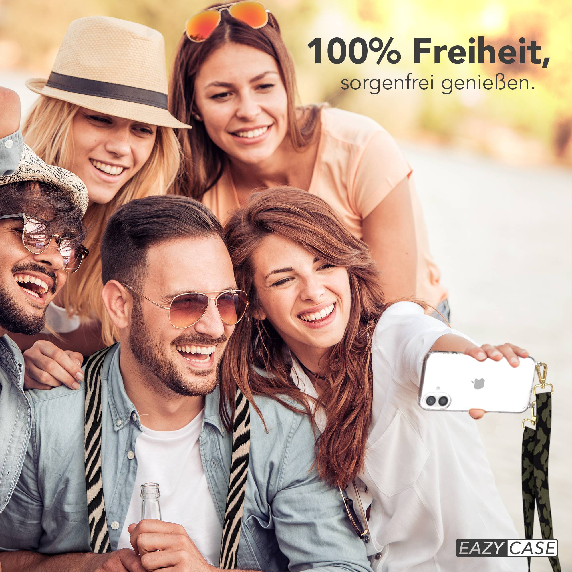 Vier Freunde lächeln und machen ein Selfie im Freien. Einer hält ein Handy.