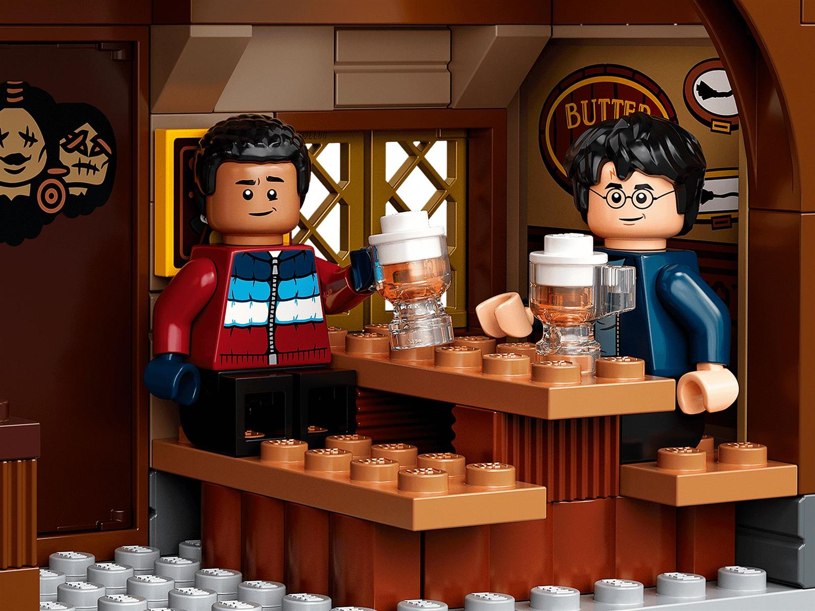 Zwei Lego-Figuren stehen an einer Bar und halten schaumige Getränke. Einer trägt eine rote Jacke, der andere eine blaue.