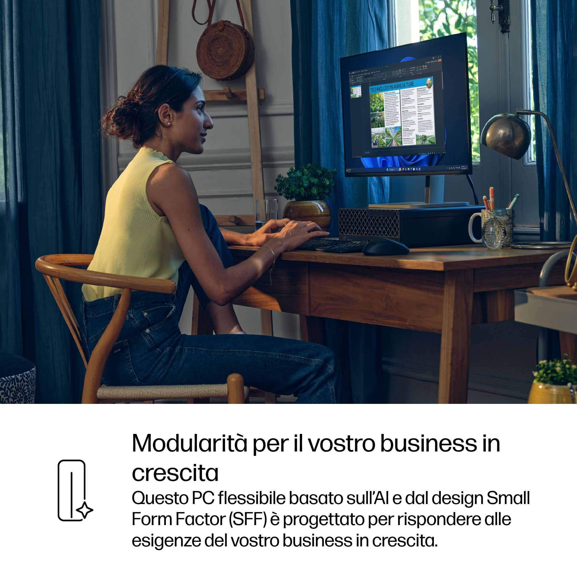 Una donna siede alla scrivania lavorando al computer. Lo schermo mostra una presentazione.