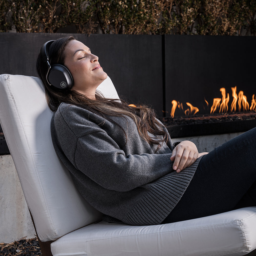 Femme avec un casque assise dans un fauteuil écoutant de la musique près d'un brasero.
