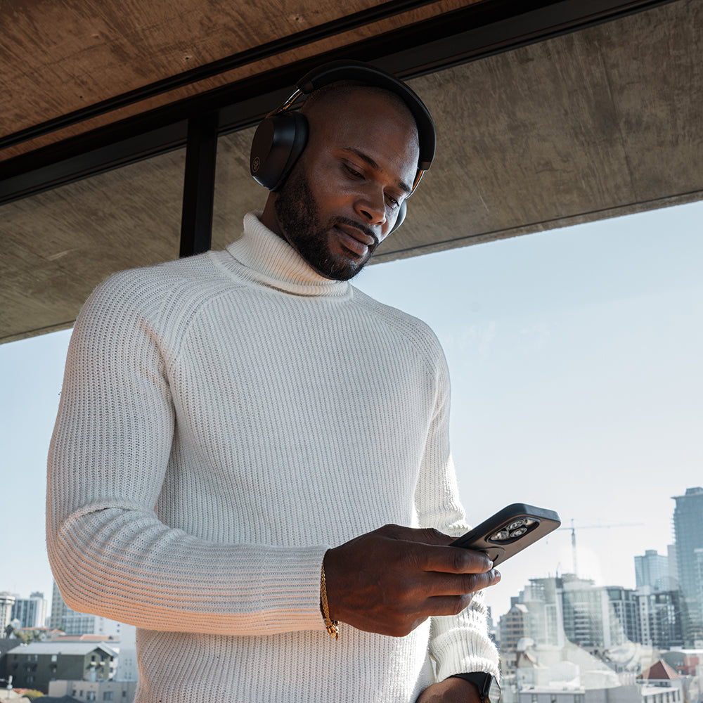 Un homme portant un casque et un col roulé blanc regarde son téléphone.