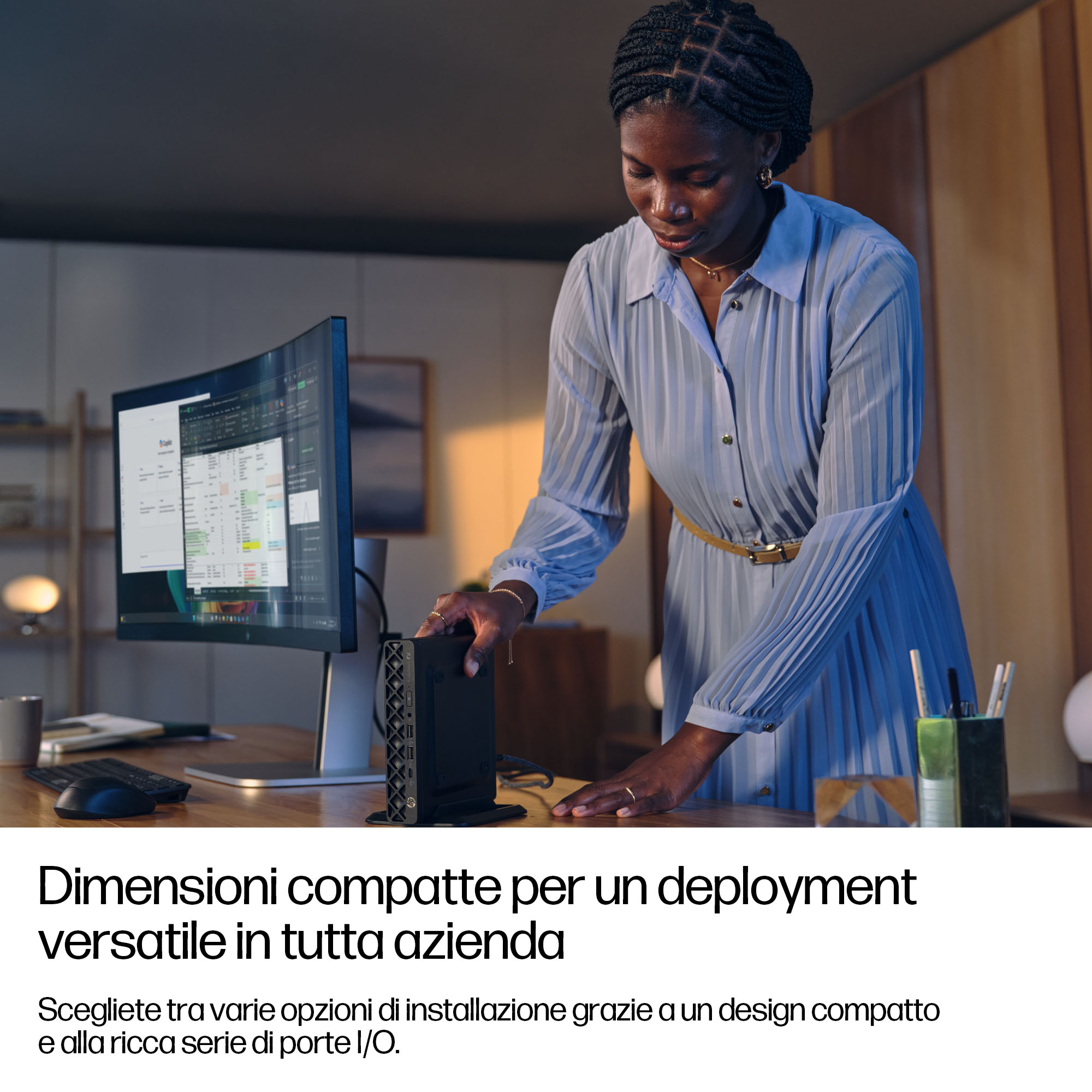 Una donna con i capelli intrecciati sta a una scrivania, toccando un piccolo computer.