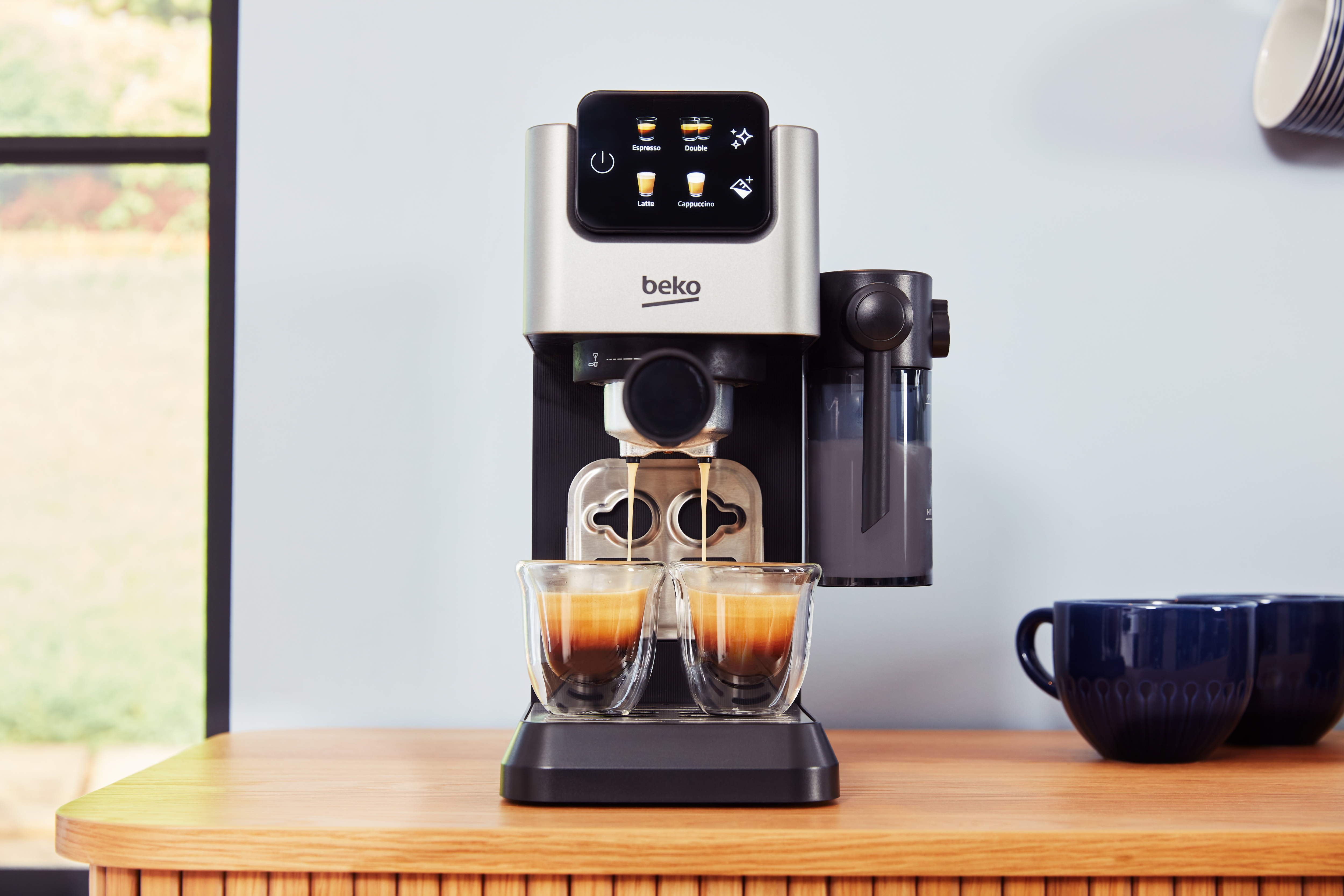 Eine Beko-Kaffeemaschine brüht zwei Espressi in Glasbechern.