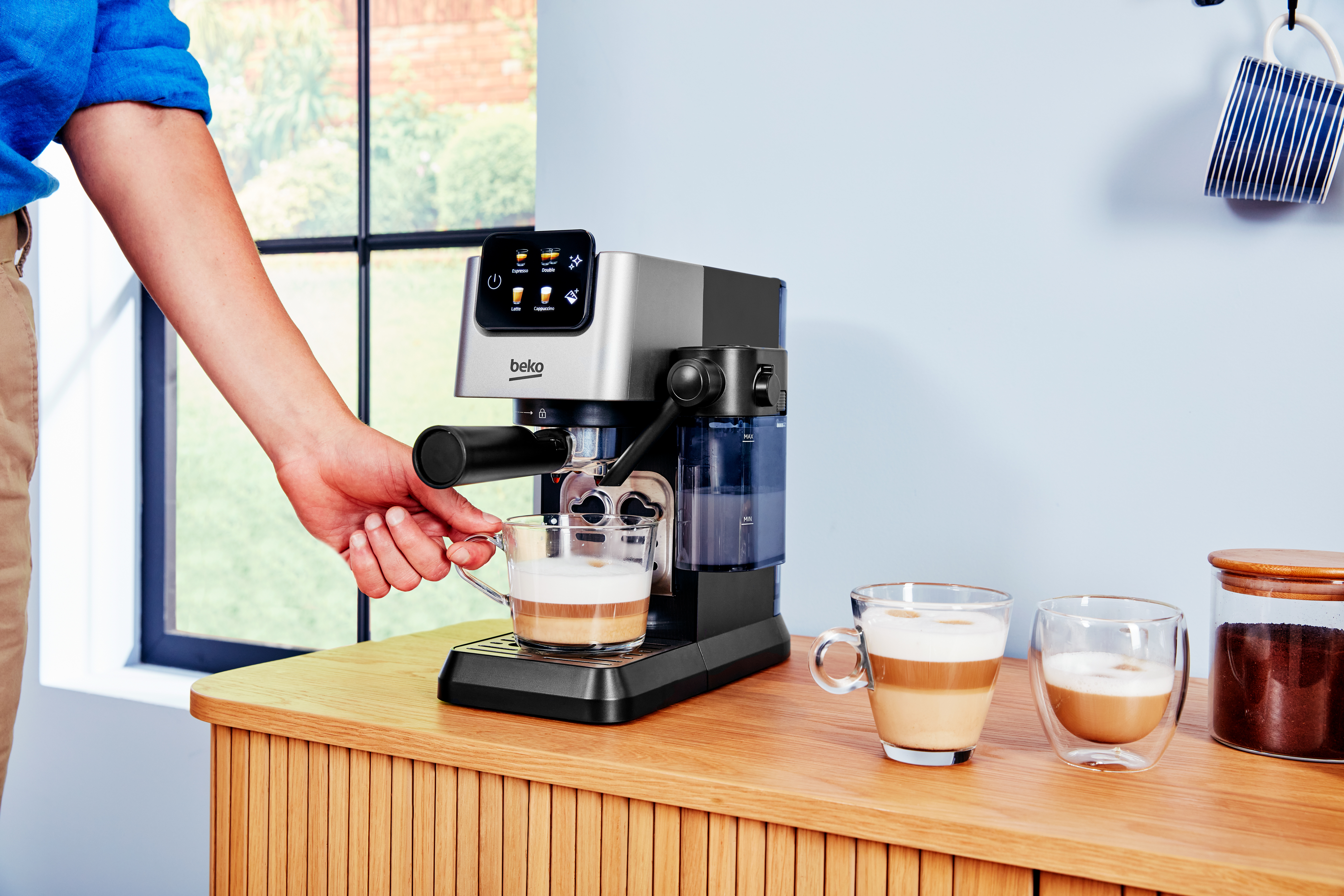 Eine Person benutzt eine Kaffeemaschine, um einen Latte Macchiato zuzubereiten.