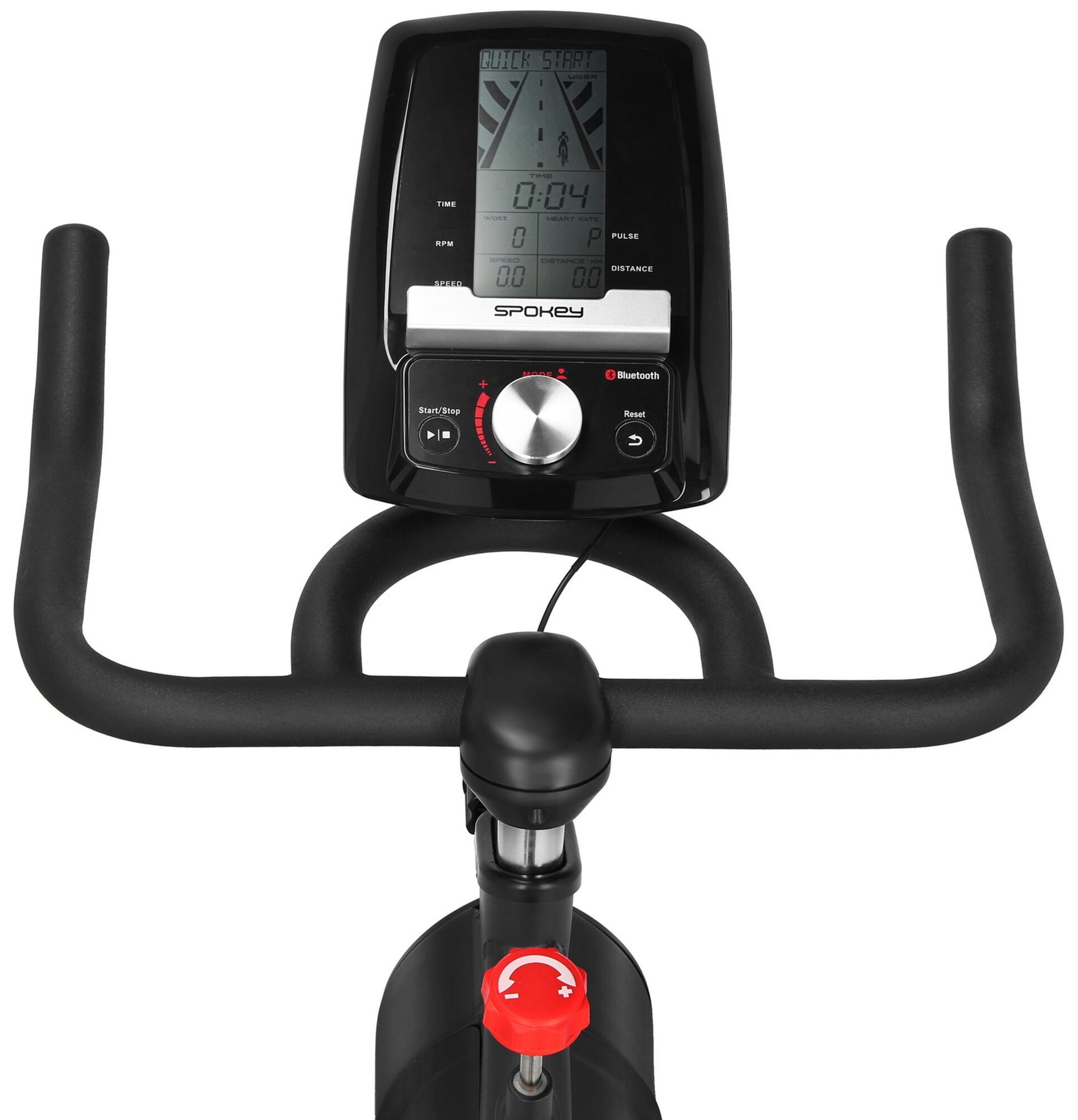 La pantalla de una bicicleta estática Spokey muestra tiempo, vatios, frecuencia cardíaca, RPM, velocidad y distancia.