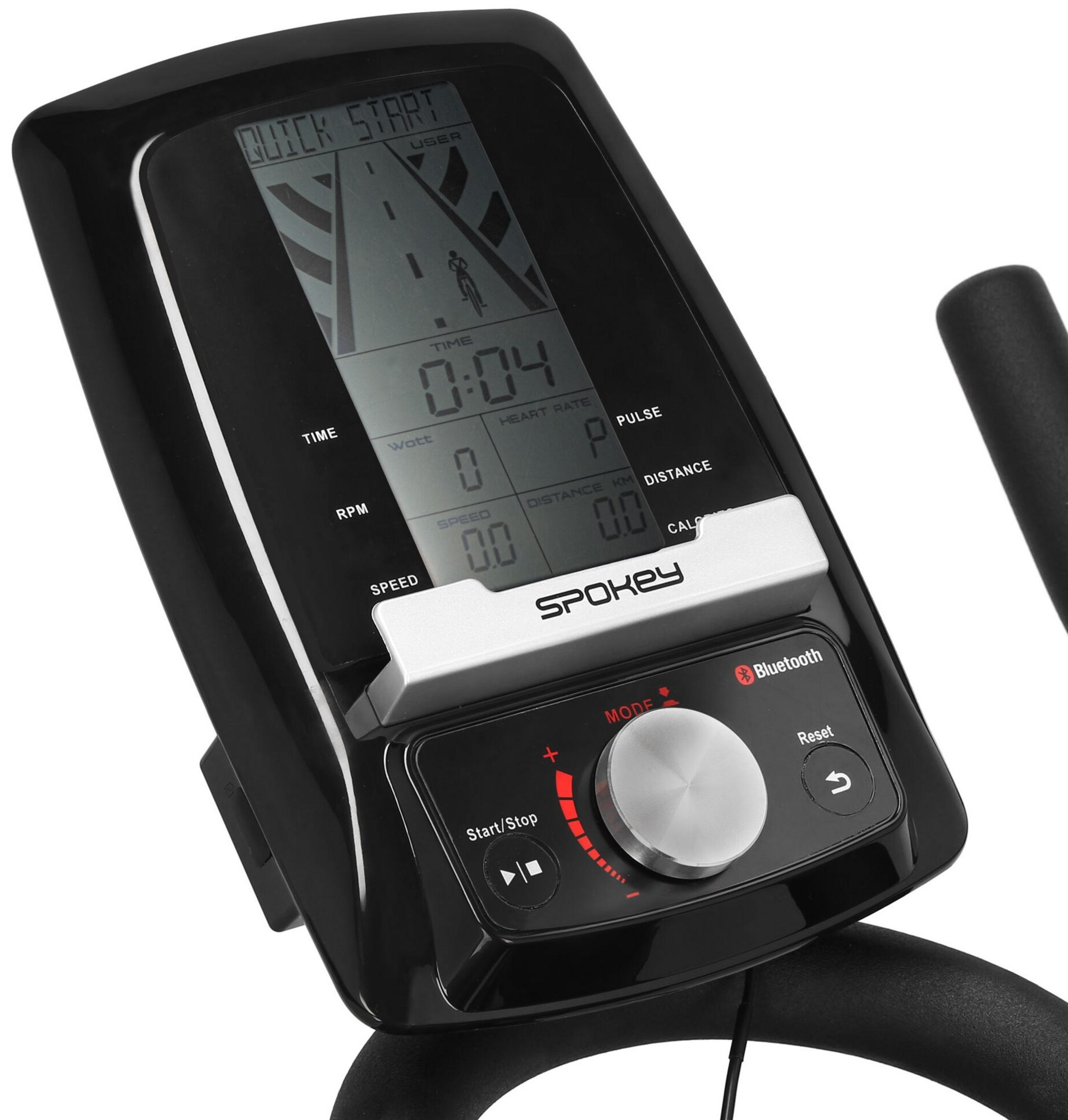 La consola negra de una bicicleta estática Spokey muestra tiempo, velocidad, ritmo cardíaco y distancia.