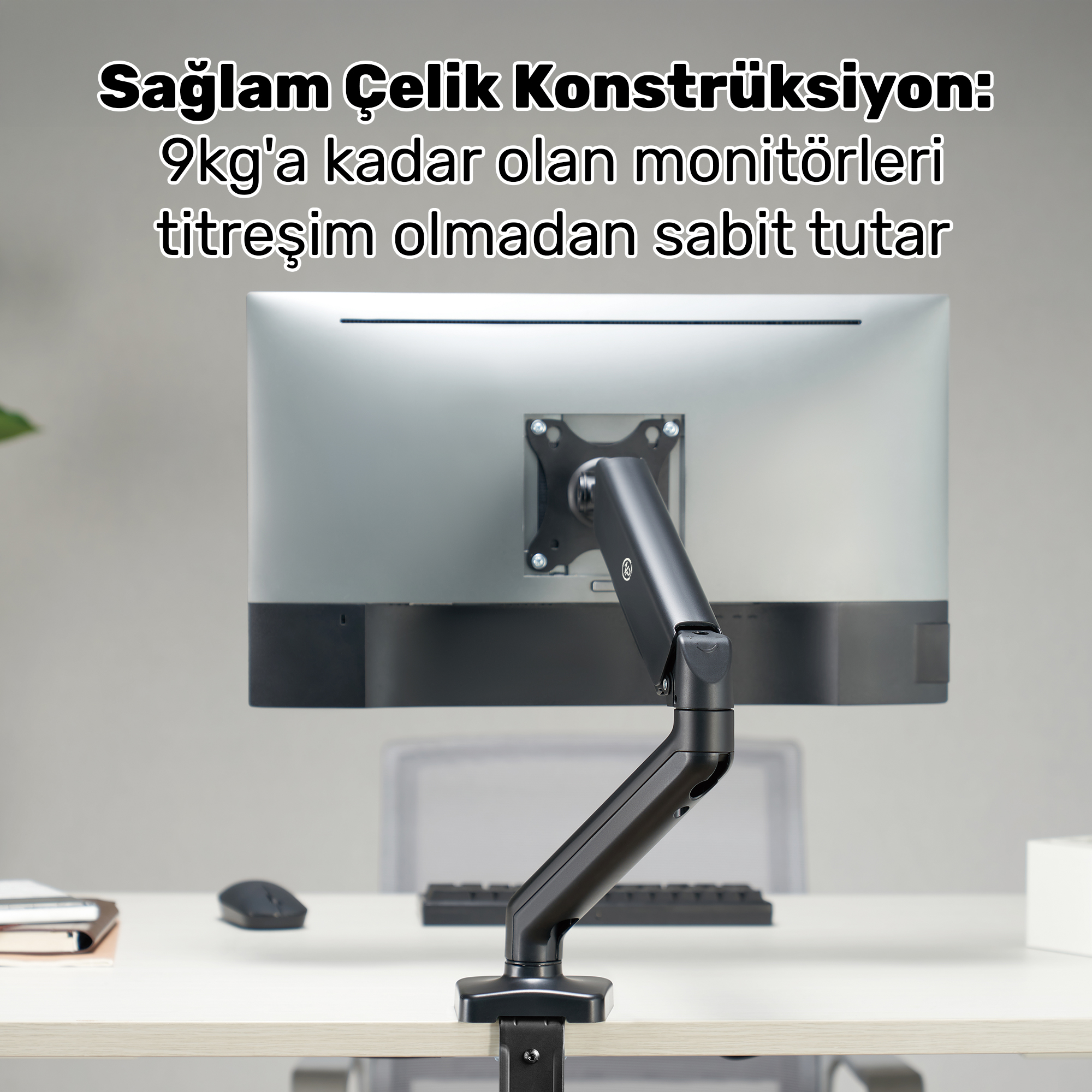 Gümüş renkli bir monitör, masaya monte edilmiş siyah bir kola takılıdır.