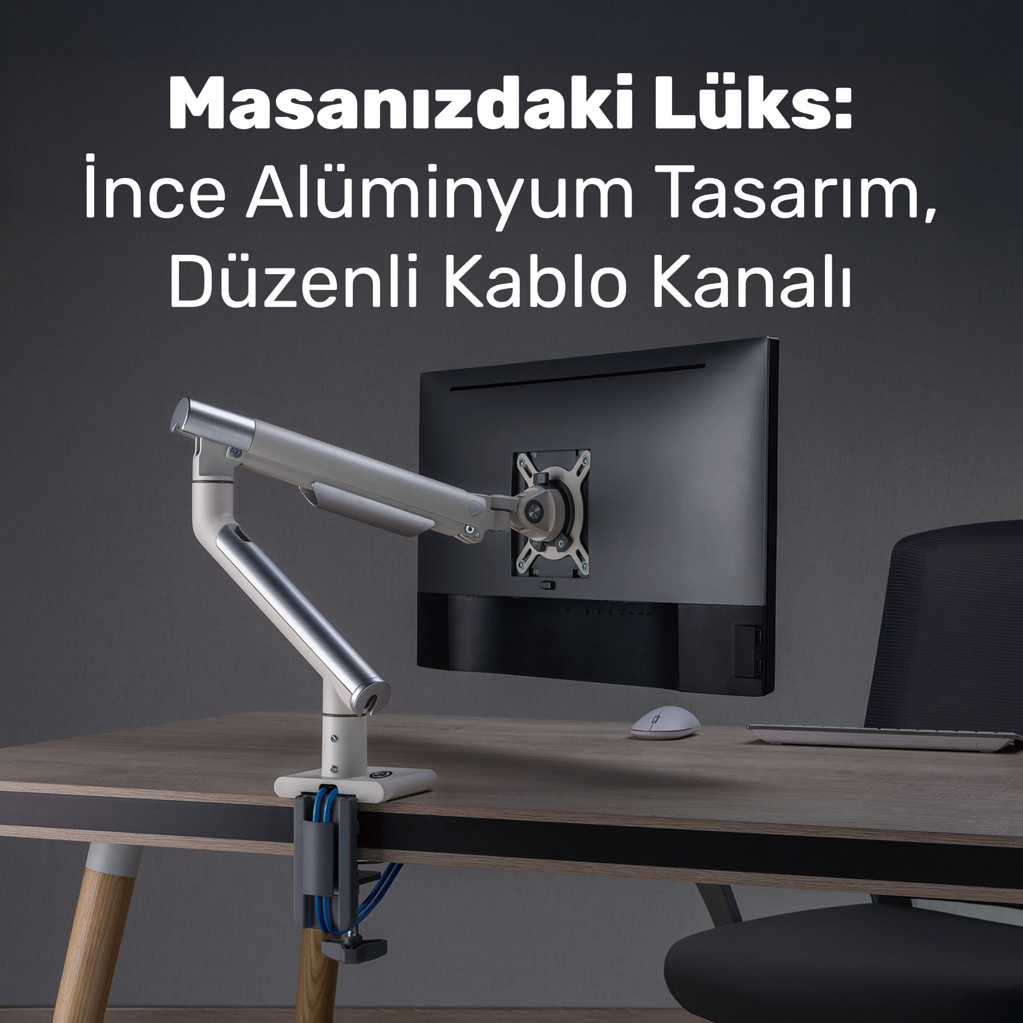 Bir monitör kolu, beyaz fare ve klavyeli ahşap bir masada siyah bir monitörü tutuyor.