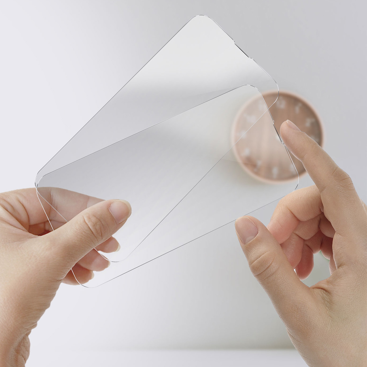 Deux mains tiennent des feuilles de plastique transparentes. Une main tient la feuille gauche, l'autre touche la droite.