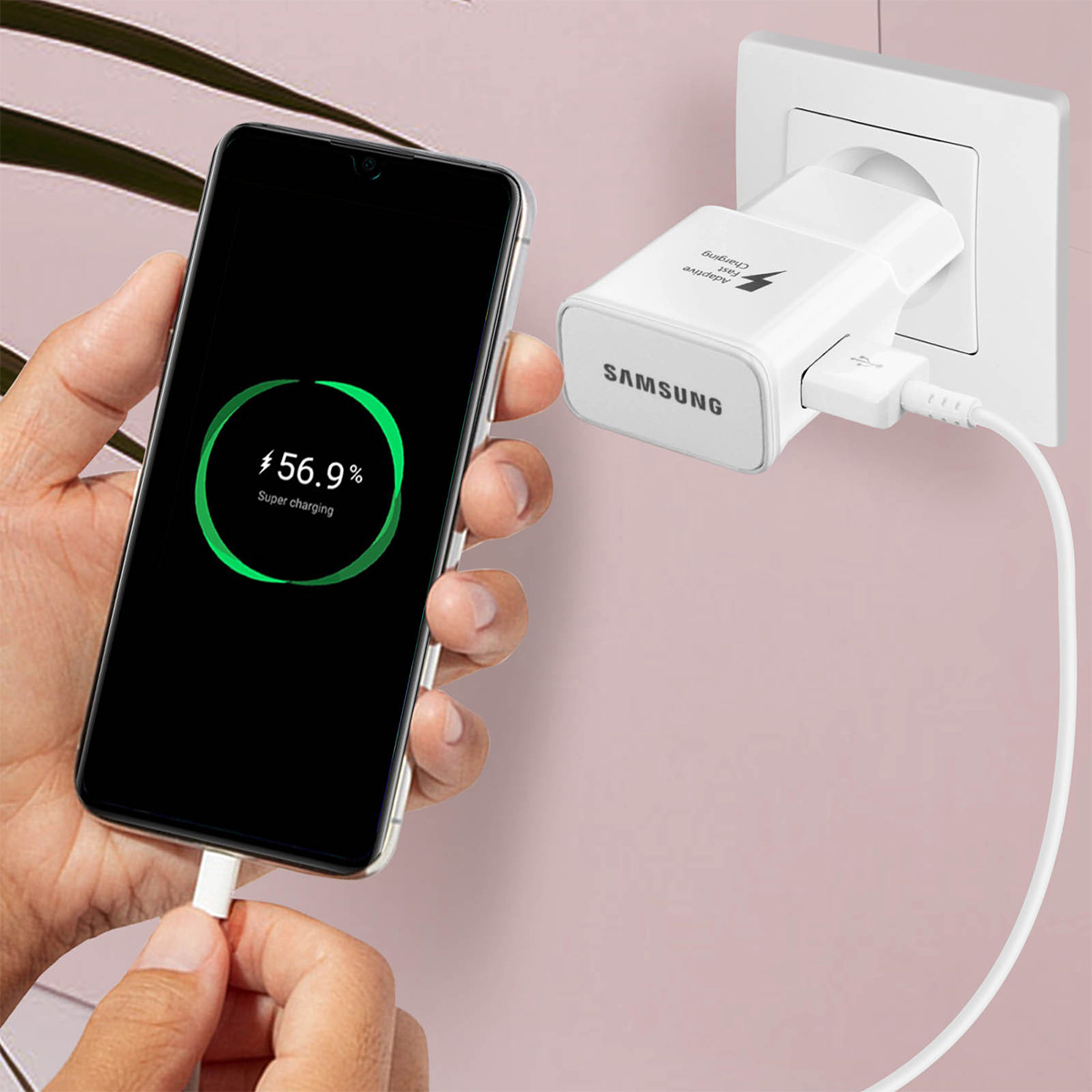 Una mano tiene un telefono collegato a un caricabatterie Samsung bianco.