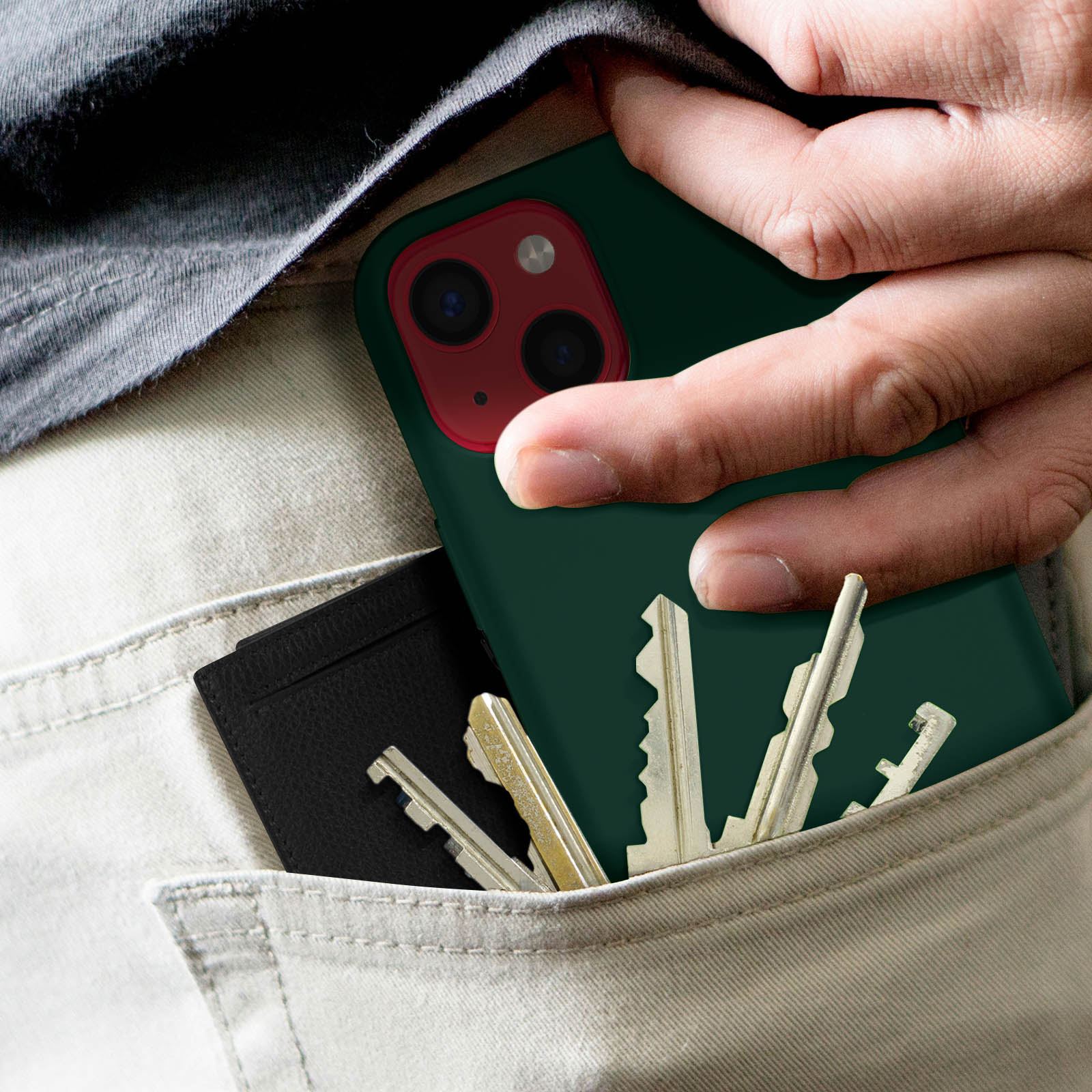 Una mano mette un telefono e chiavi nella tasca di pantaloni chiari.