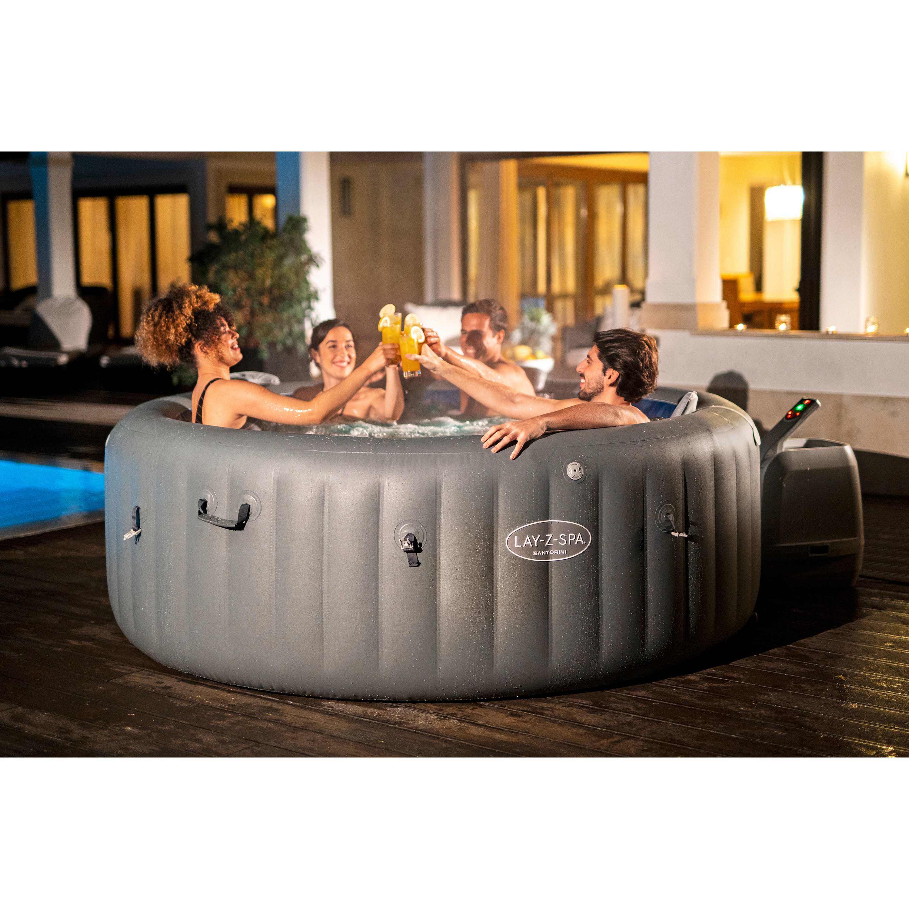 Vier Personen stoßen in einem aufblasbaren Whirlpool mit Getränken an.