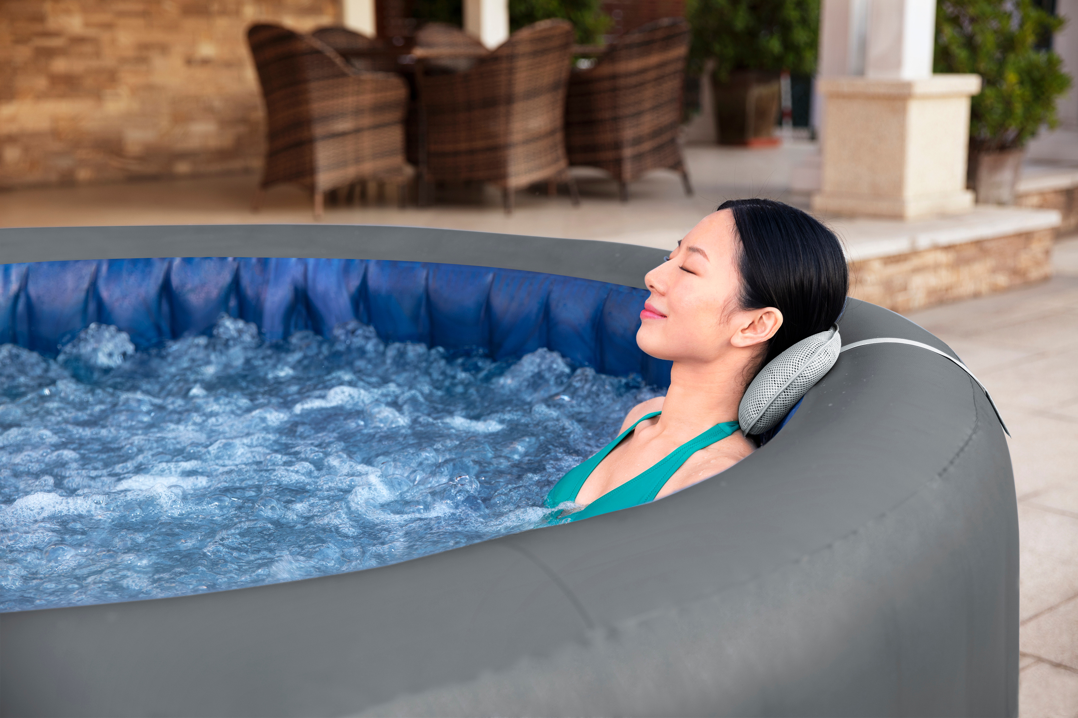 Frau entspannt sich in einem aufblasbaren Whirlpool im Freien mit sprudelndem Wasser.