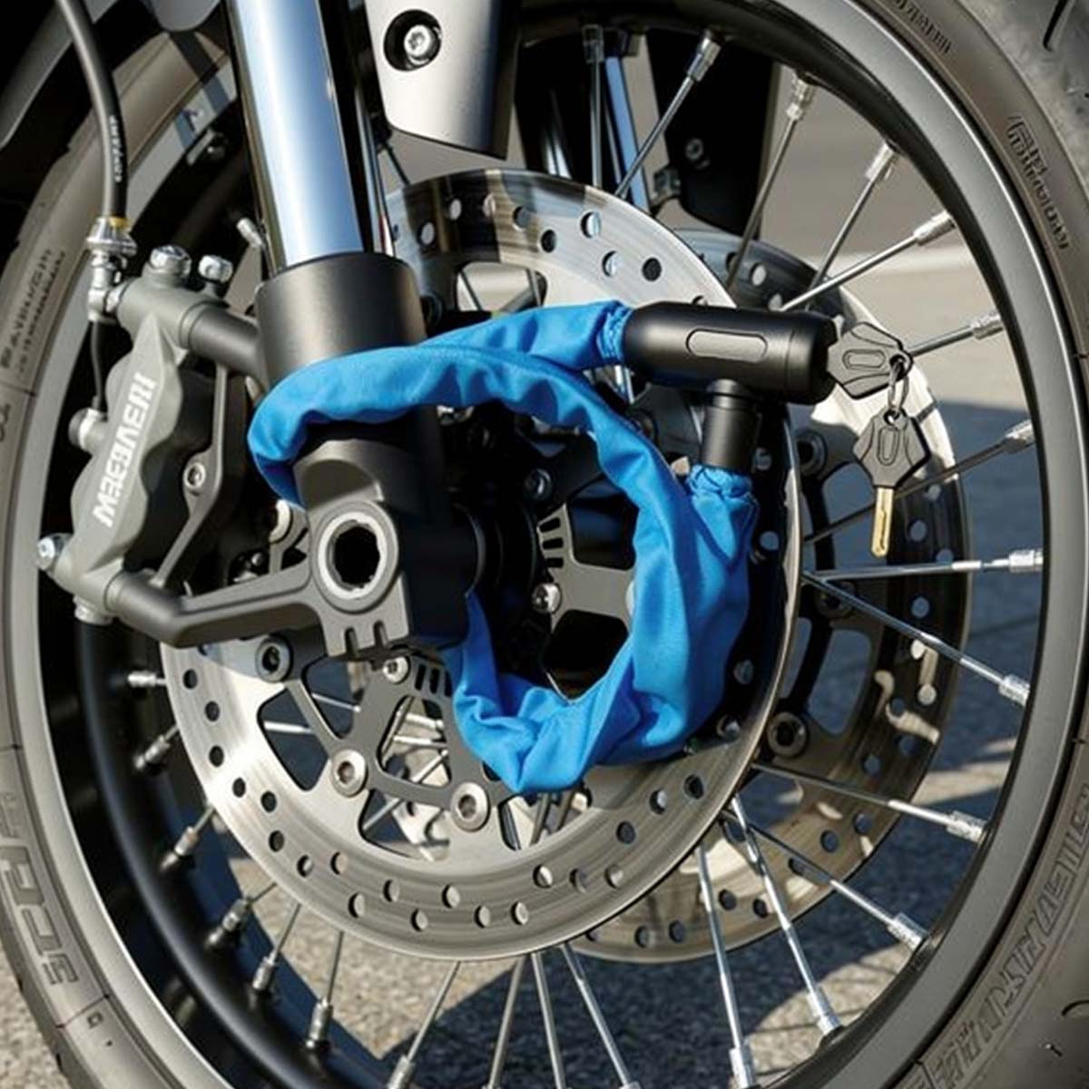 Ein blaues Kettenschloss sichert die Bremsscheibe eines Motorrads.