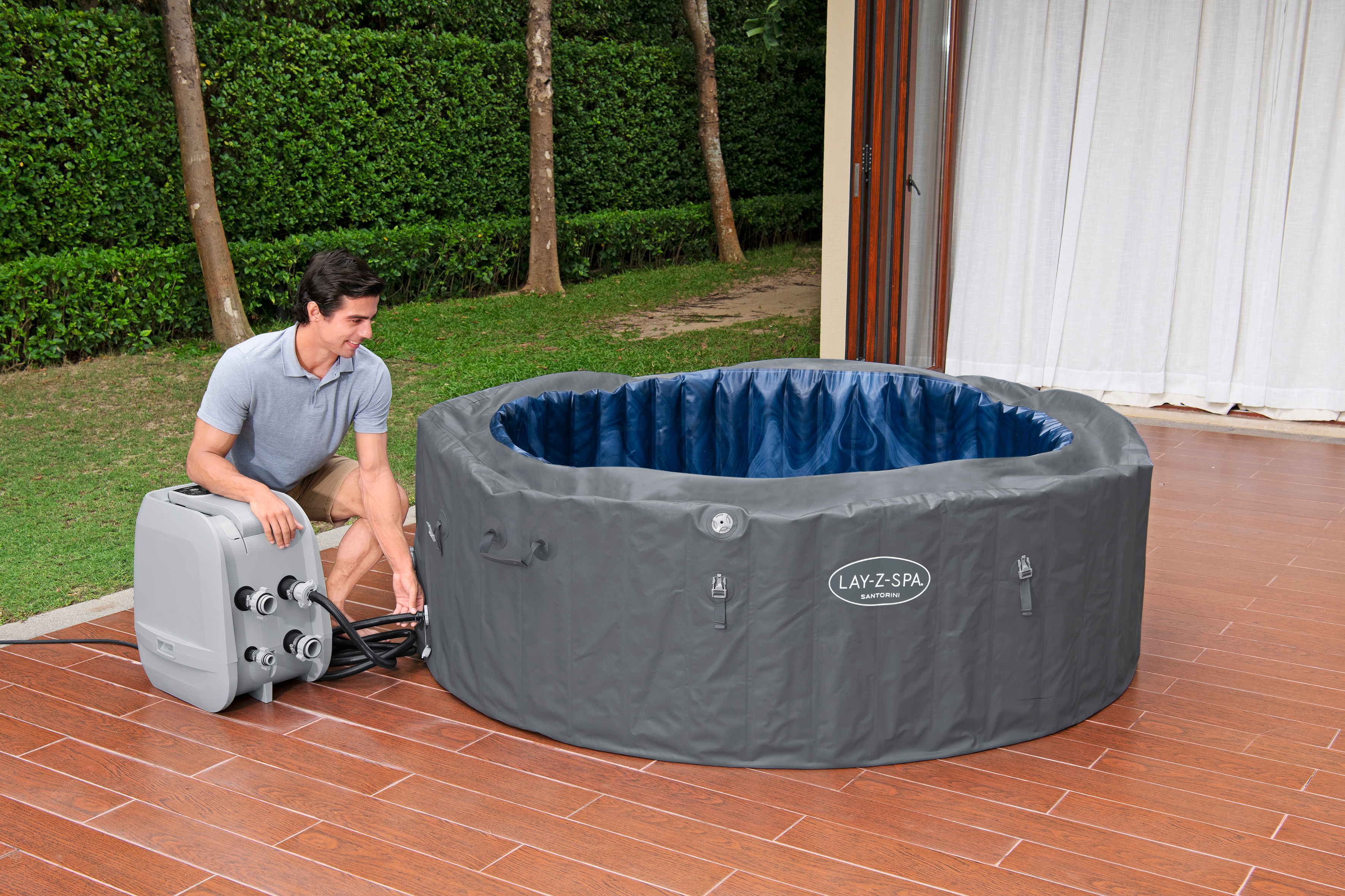 Mann verbindet Pumpe mit aufblasbarem Whirlpool im Freien auf Holzterrasse.