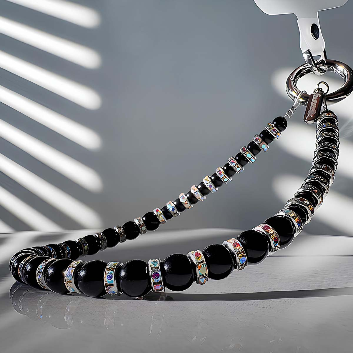 Una collana di perle nere con accenti di cristallo pende da un anello d'argento.