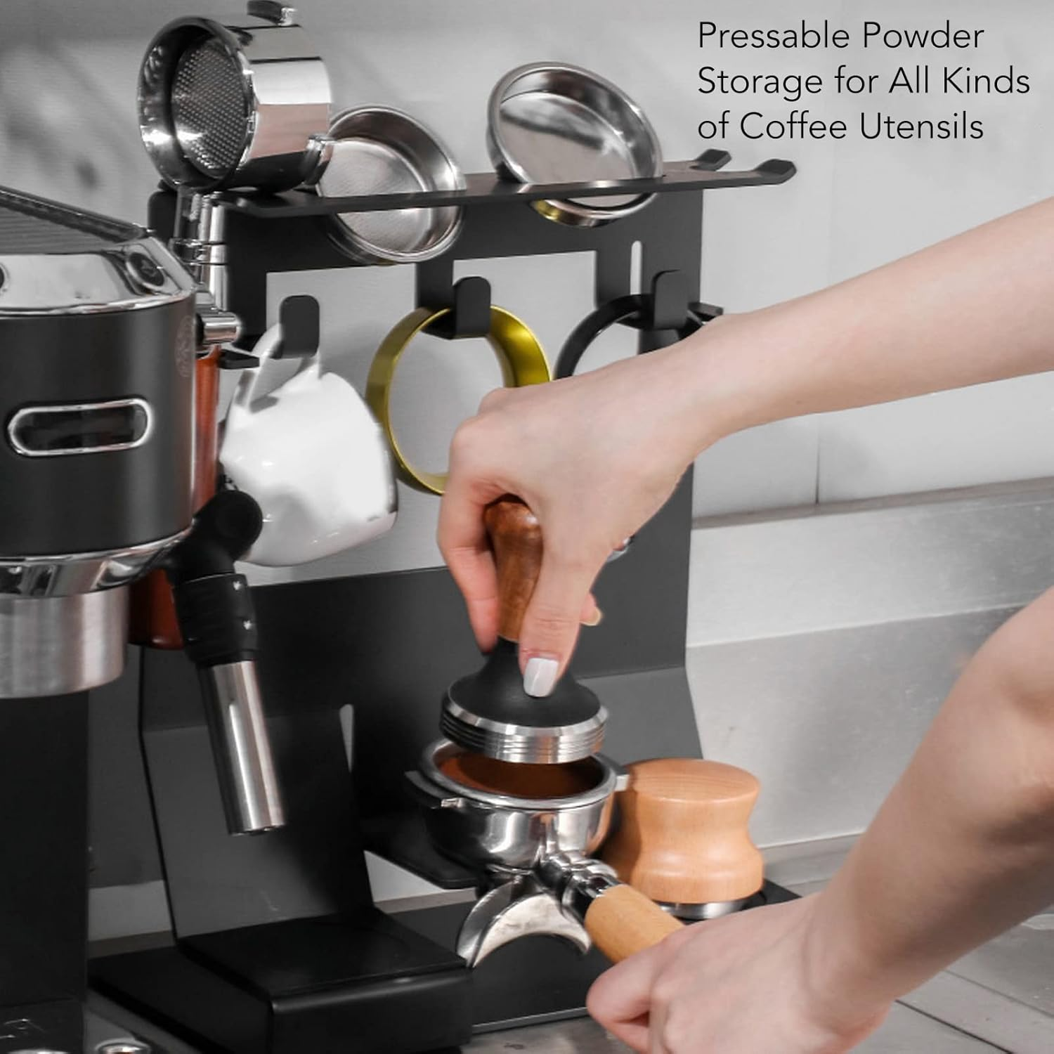Eine Hand benutzt einen Tamper auf einem Siebträger neben einer Espressomaschine.