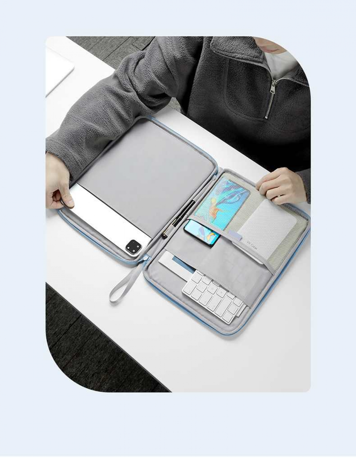 Eine Person packt ein Tablet, ein Smartphone, eine Tastatur und einen Stift in eine blaue Tasche.