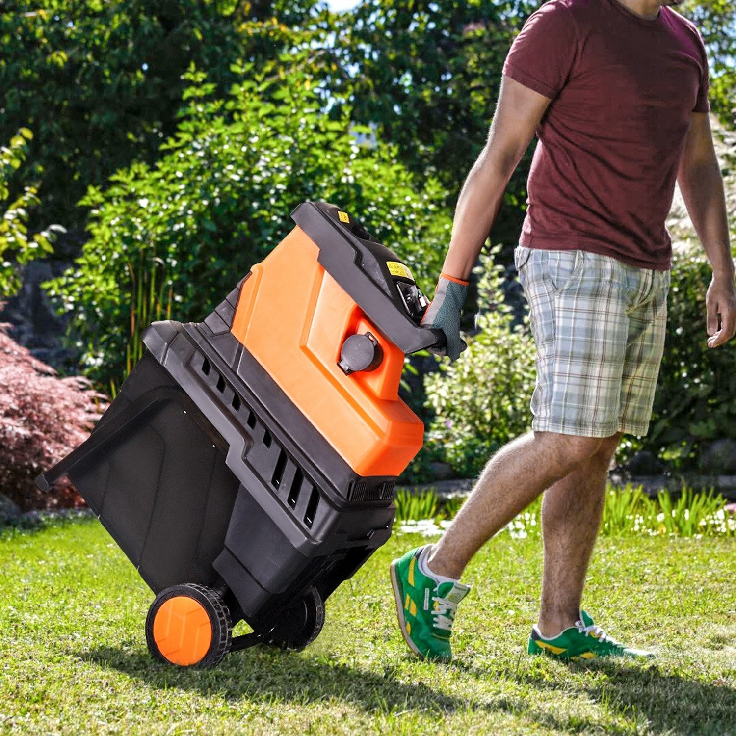 Mann schiebt einen orange-schwarzen Häcksler über einen grünen Rasen.