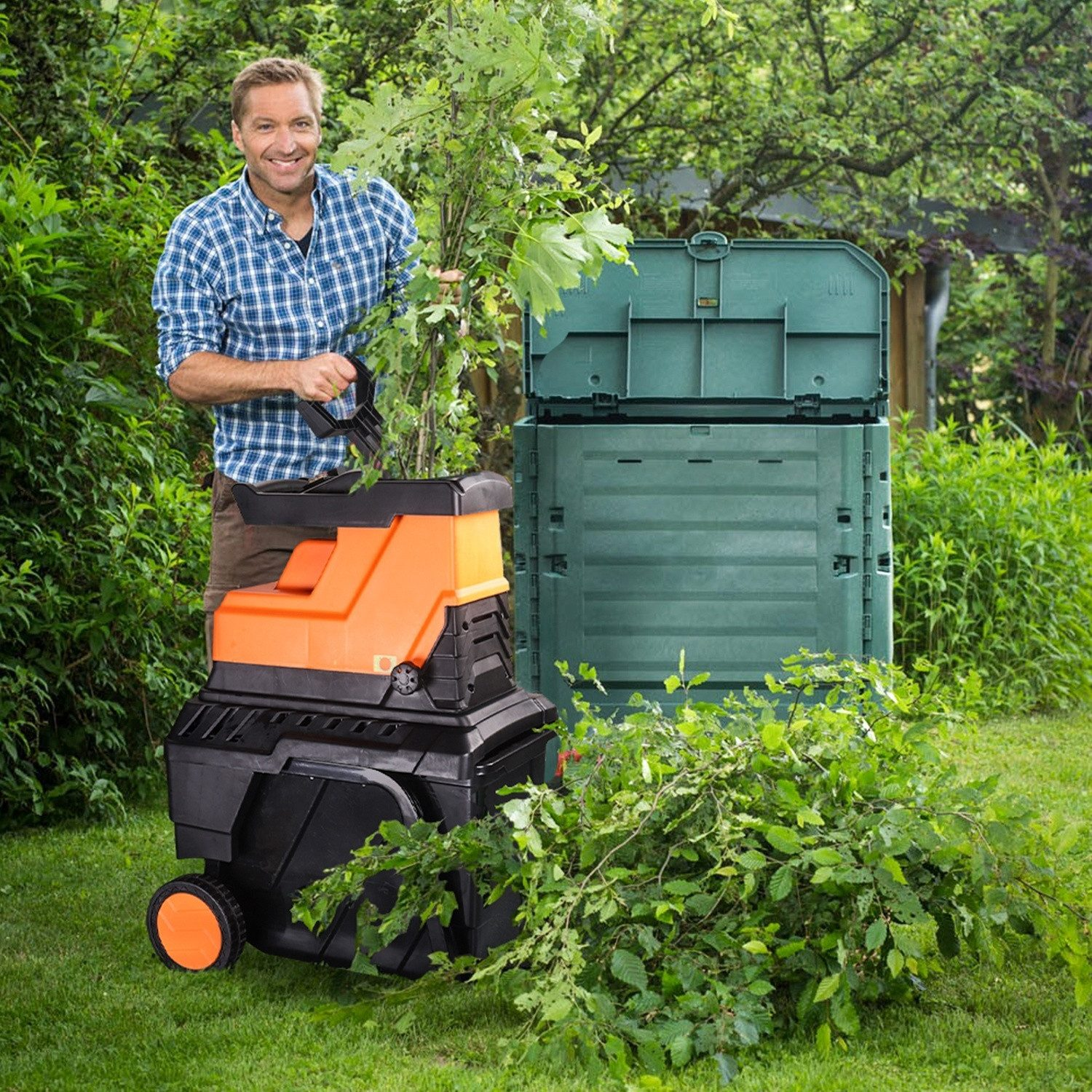 Mann mit Häcksler und Komposter im Garten, hält Zweige.