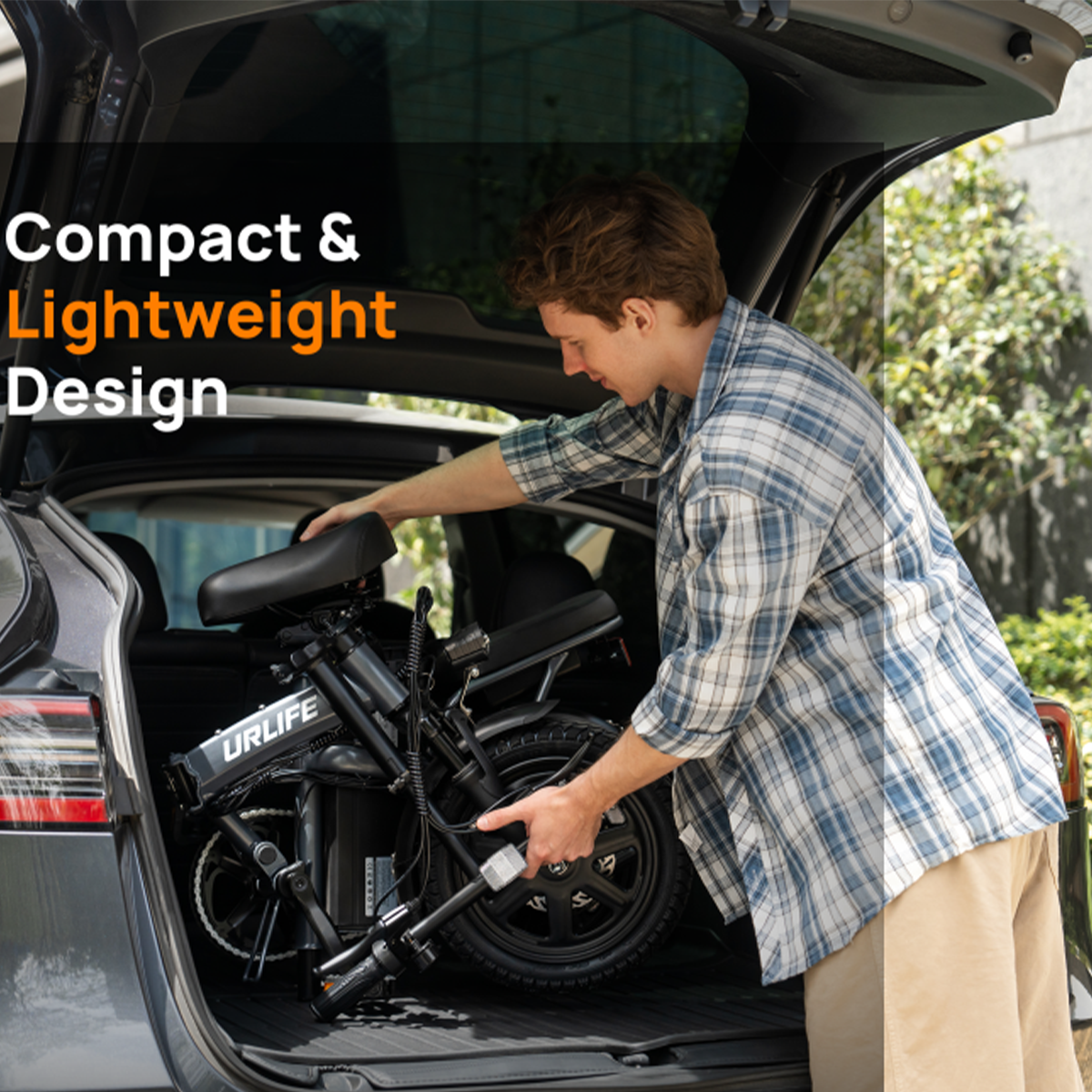 Mężczyzna ładuje czarny rower składany do ciemnego bagażnika samochodu.