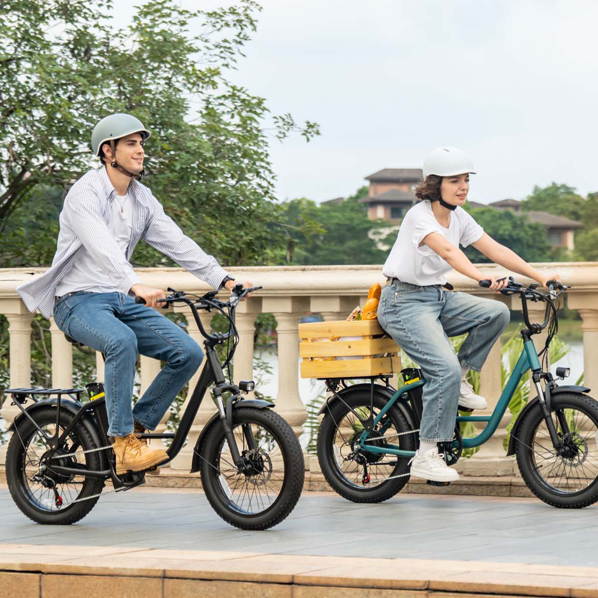 Mężczyzna i kobieta jadą na rowerach elektrycznych z grubymi oponami i kaskami, drewniana skrzynka na rowerze.
