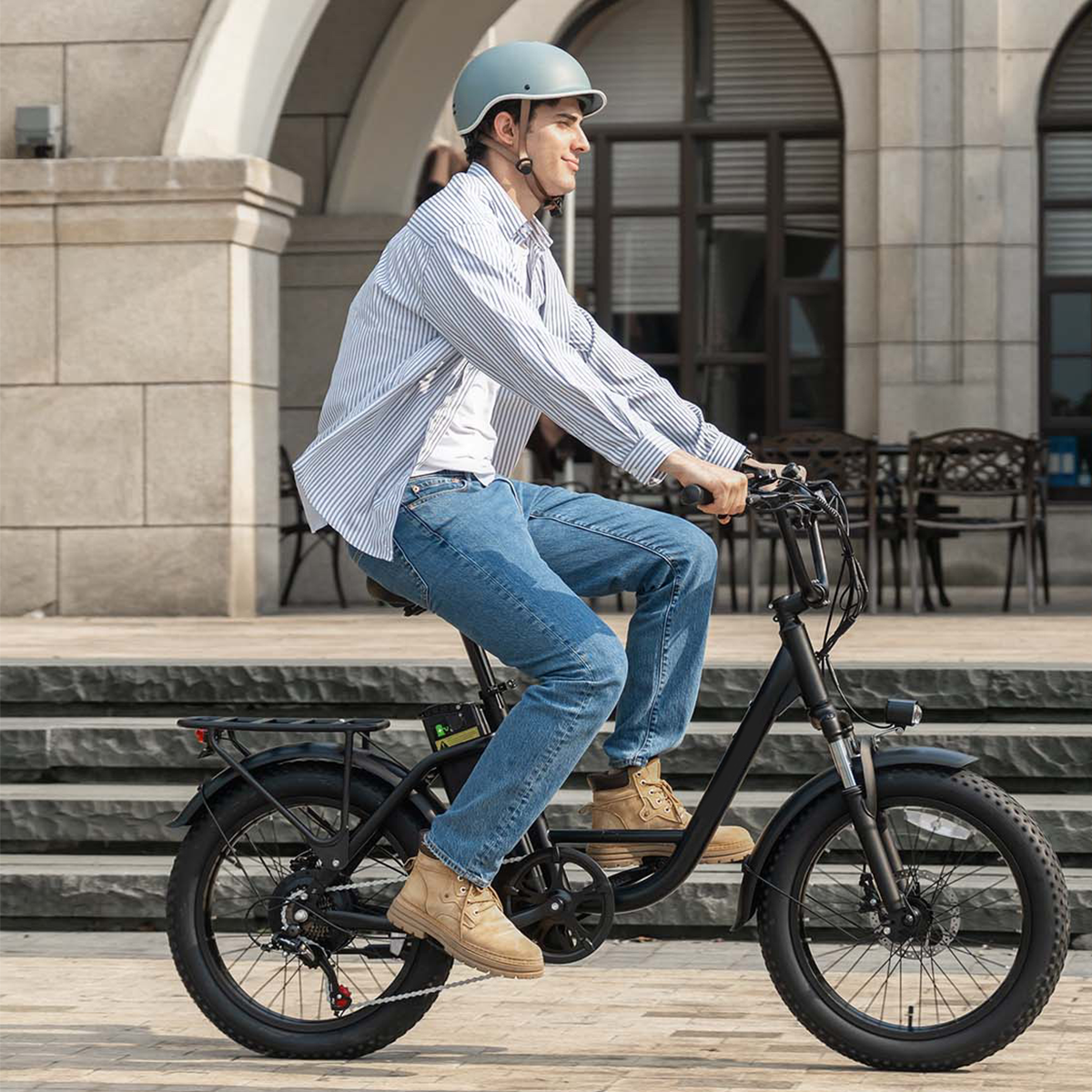 Mężczyzna w kasku jedzie czarnym rowerem elektrycznym po kamiennych schodach.