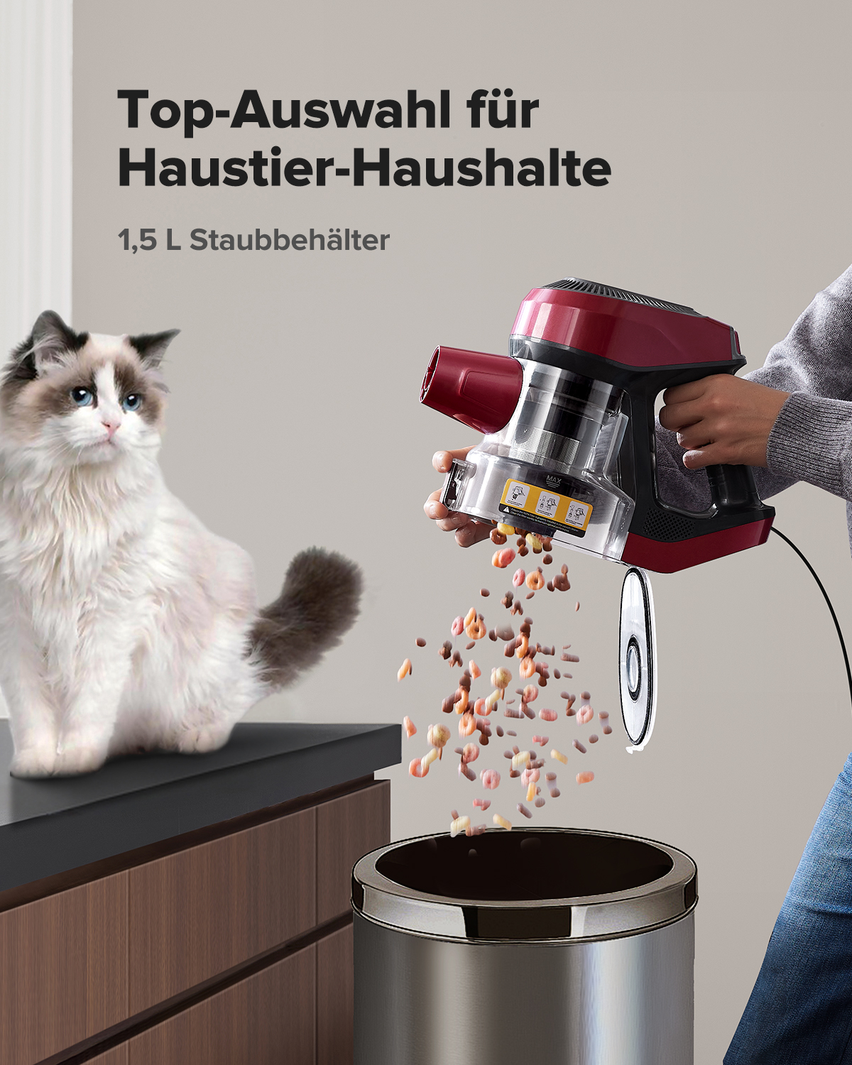 Katze sitzt neben einem Staubsauger, der Müll in einen Eimer leert.