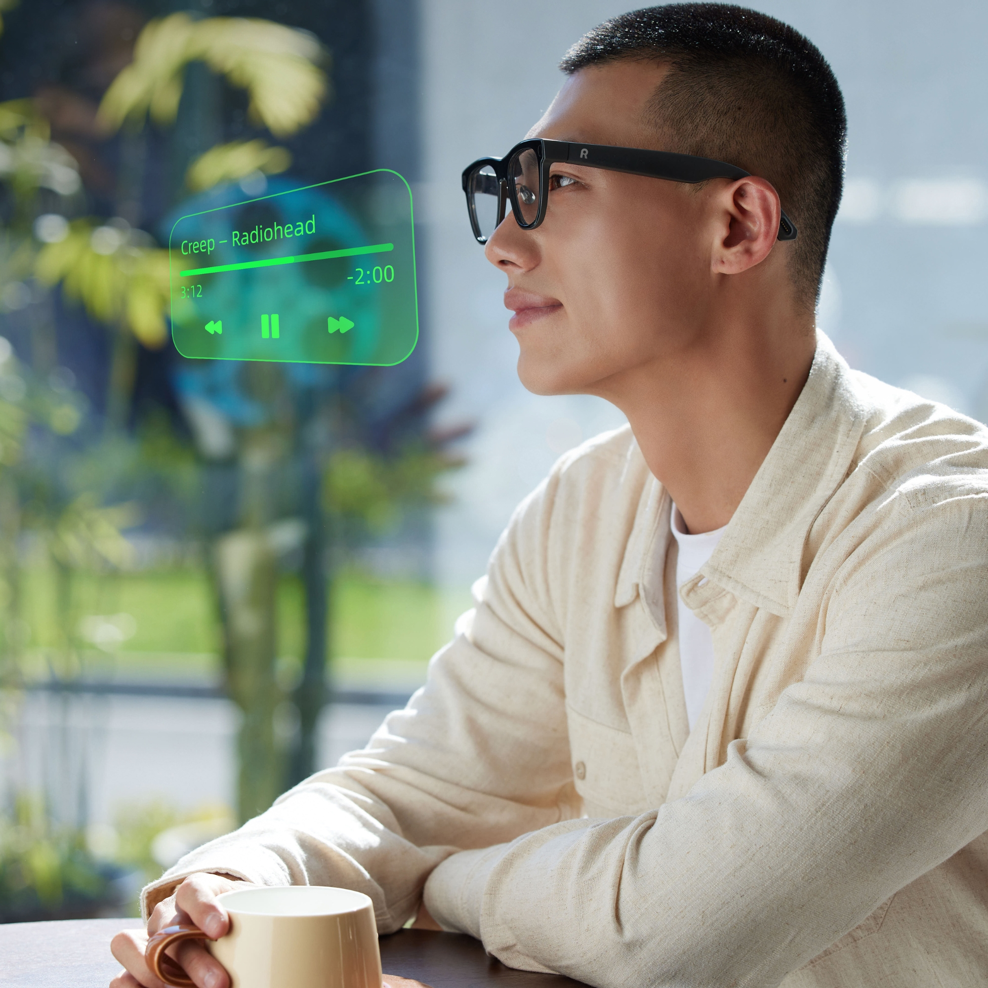 Hombre con gafas mira pantalla de reproductor de música sobre una bebida.