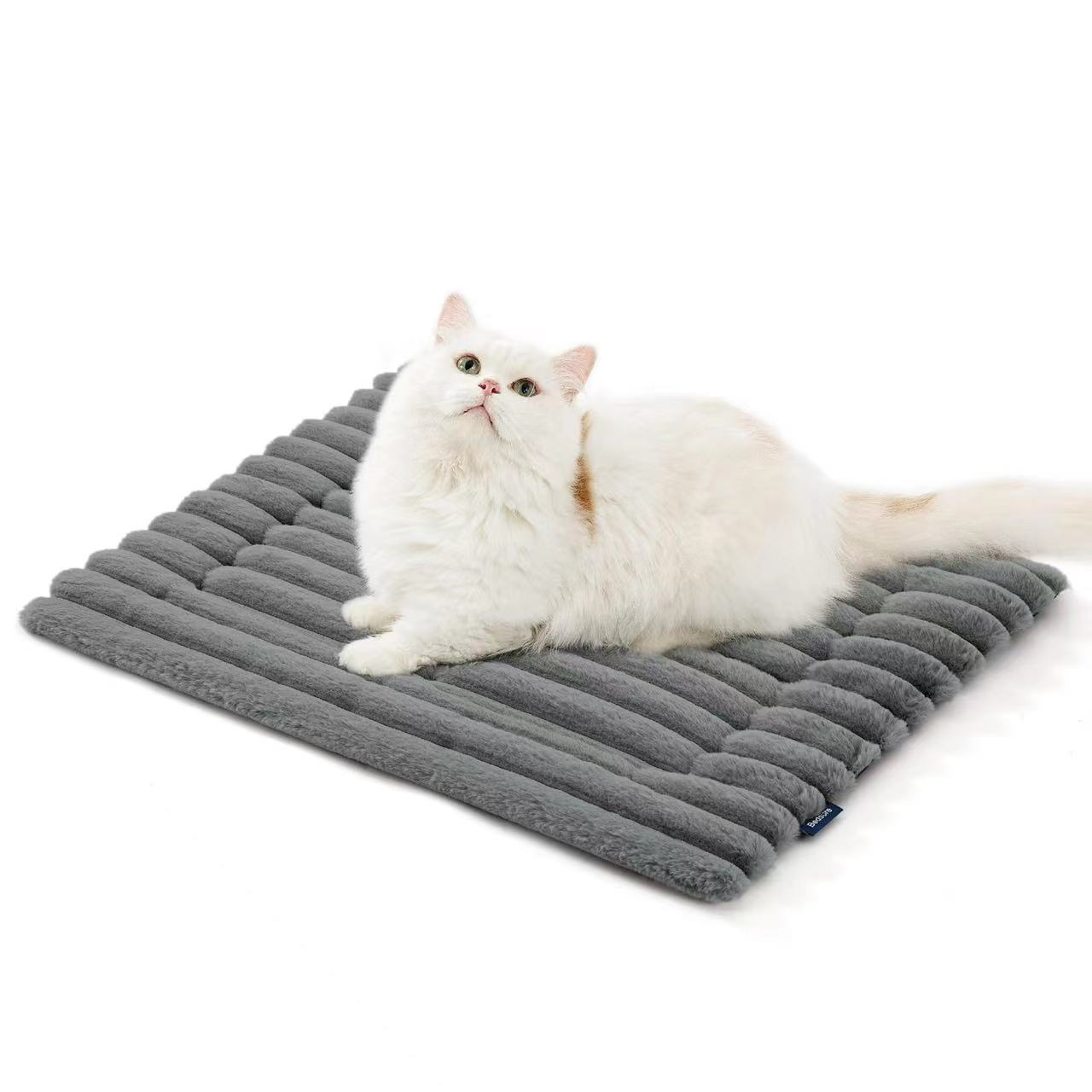 Eine weiße Katze mit orangefarbenen Flecken liegt auf einer grauen, gerippten Matte.