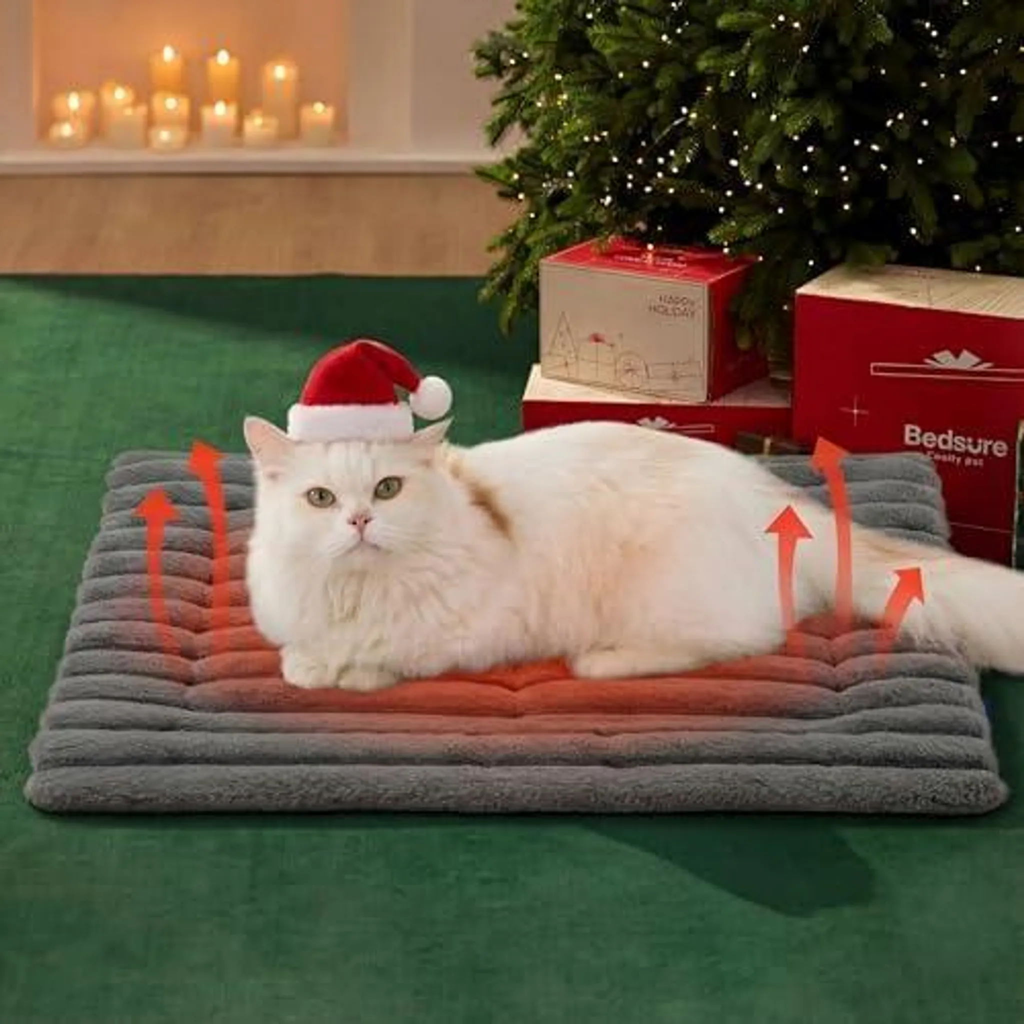 Eine weiße Katze mit Weihnachtsmannmütze liegt auf einer Heizmatte neben einem Weihnachtsbaum.