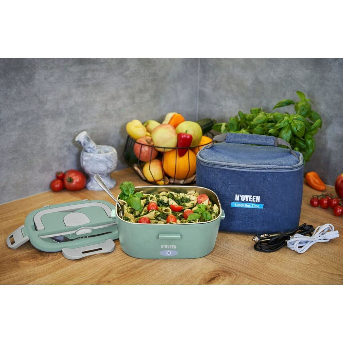 Portapranzo verde con insalata di pasta, borsa frigo blu e cavi accanto.