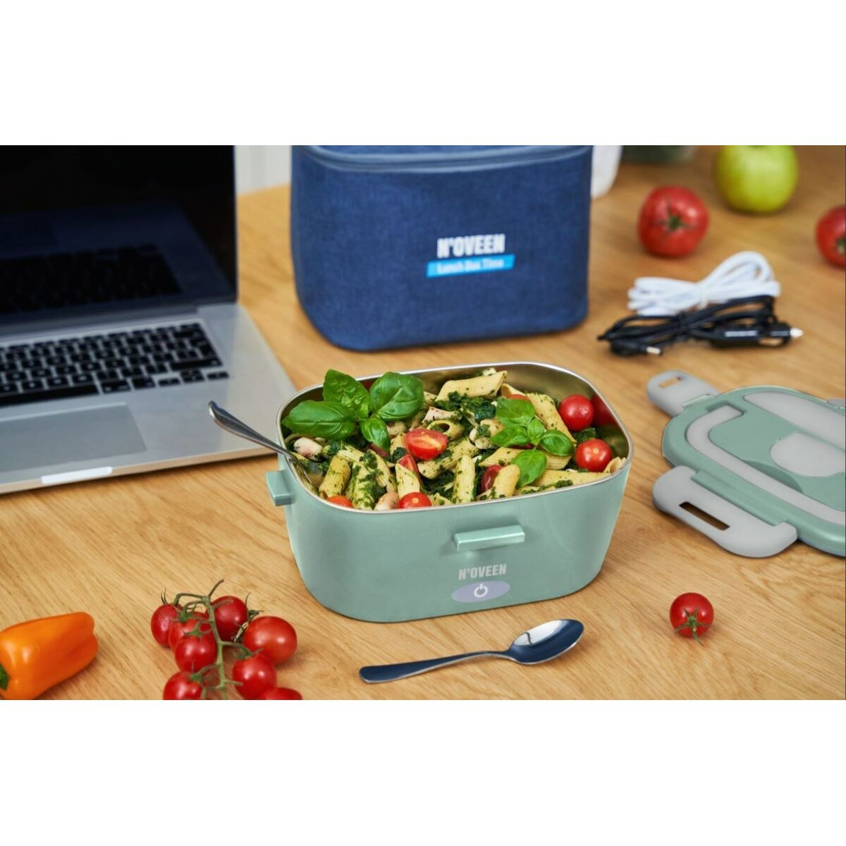 Un lunchbox N'oveen con pasta, un laptop, una mela piccola e pomodori.