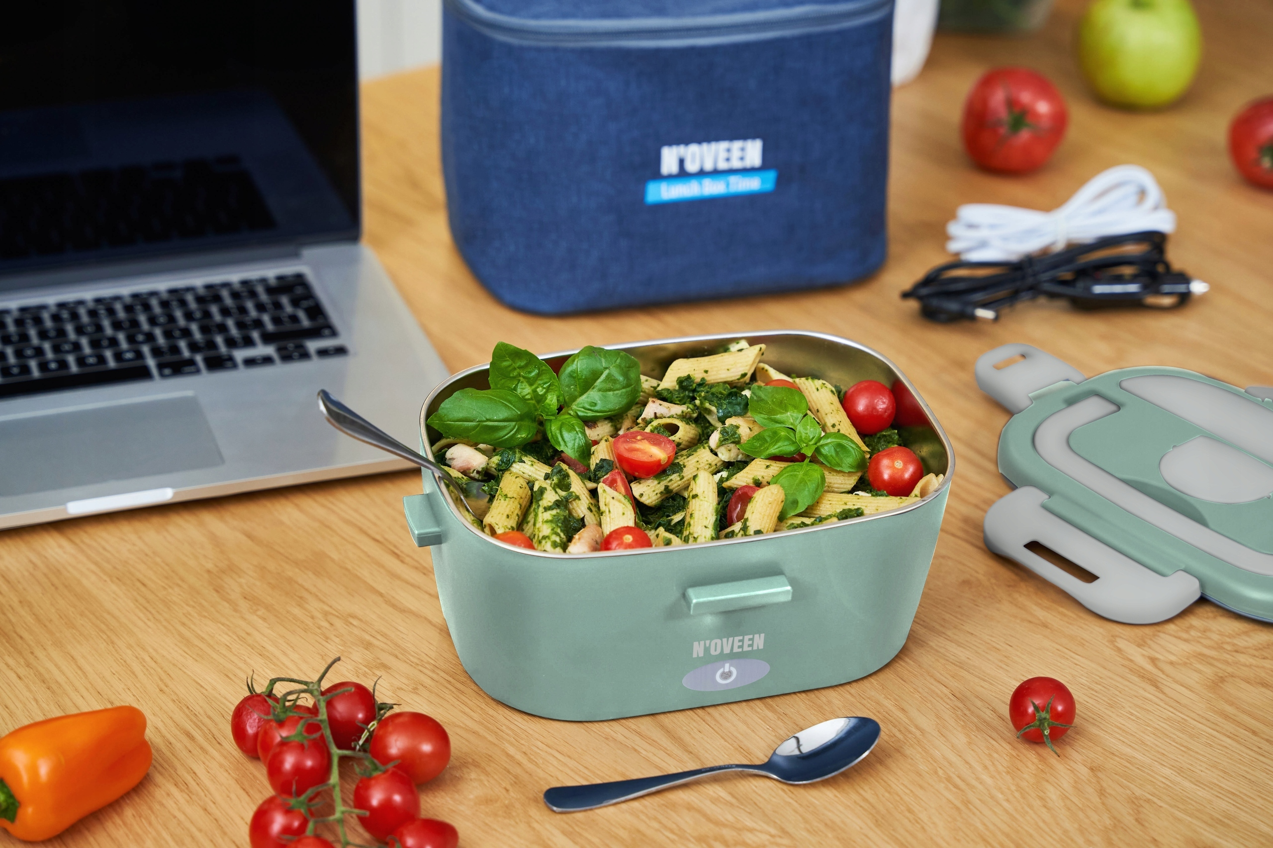 Un contenitore verde con insalata di pasta, pomodori e basilico.