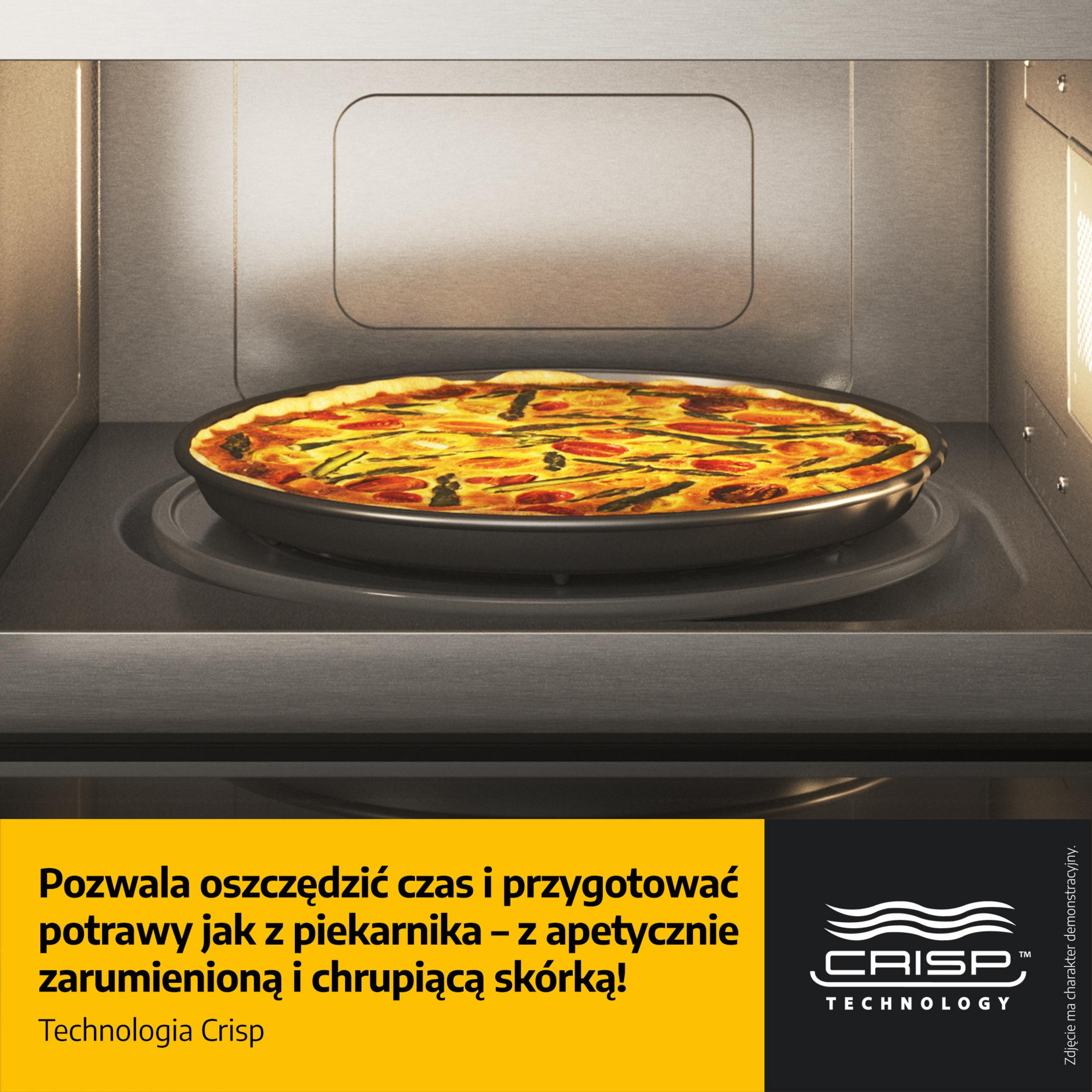 Quiche with asparagus and tomatoes inside a microwave on a turntable.