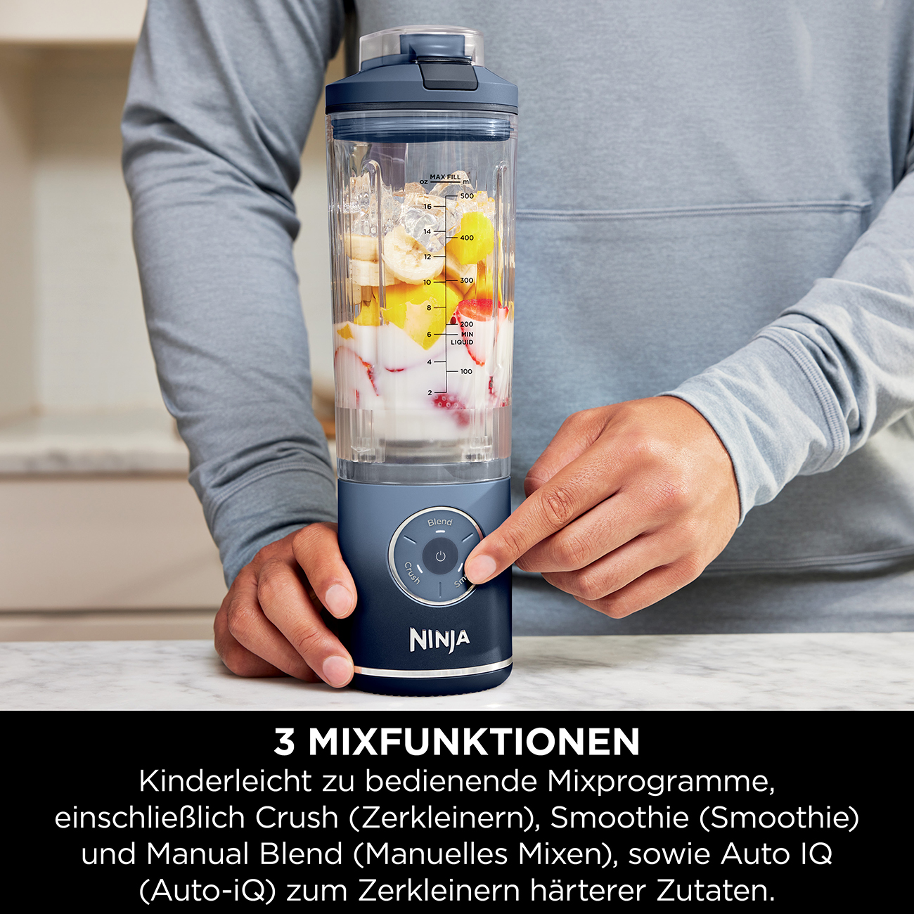 Un uomo tiene un frullatore con frutta. Il suo dito preme il pulsante 'Blend'.