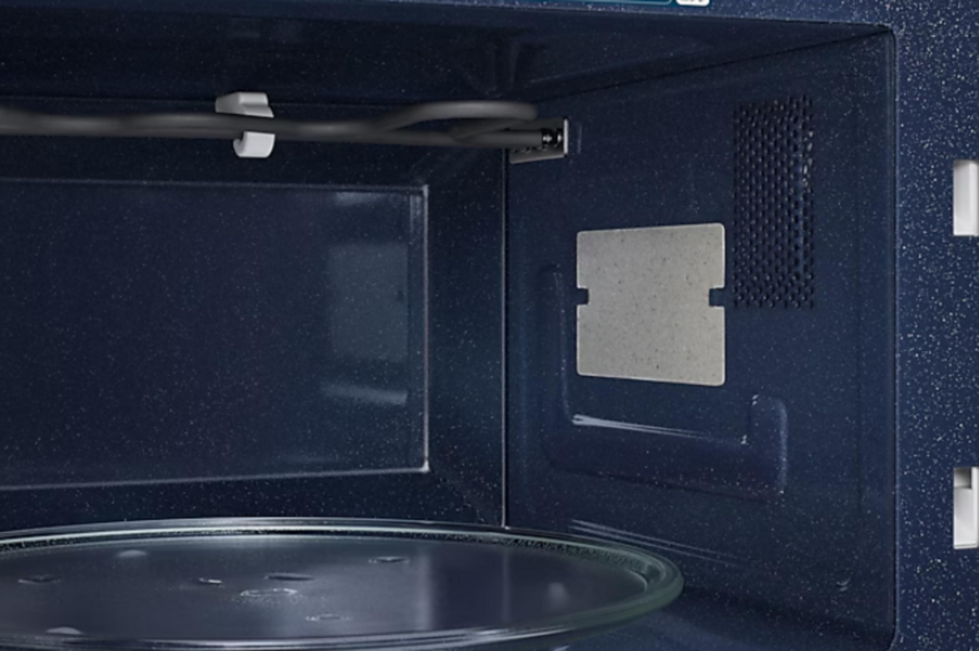 Interno di un forno a microonde con piatto girevole in vetro ed elemento riscaldante.