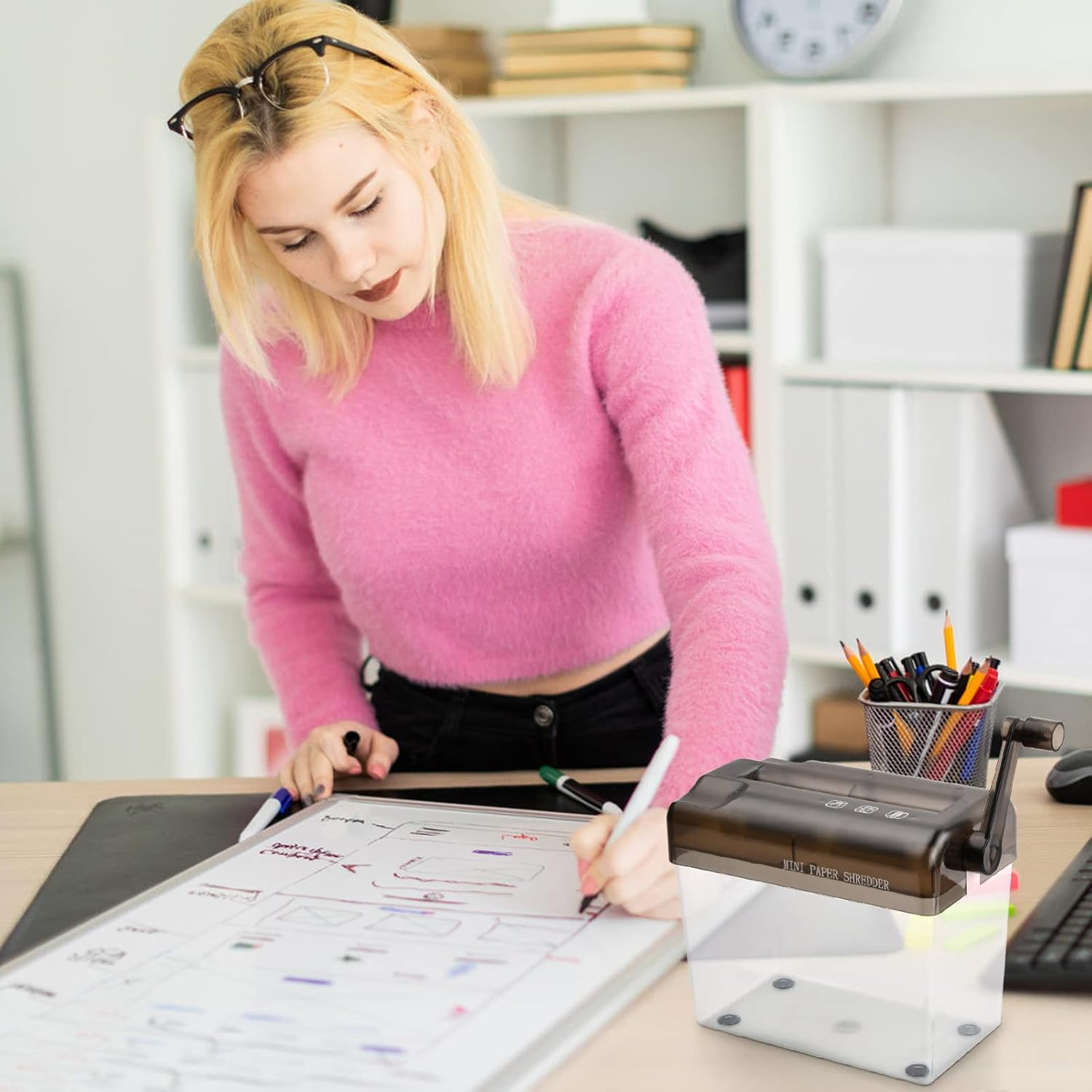 Frau mit Brille schreibt auf Whiteboard, daneben steht ein Aktenvernichter.