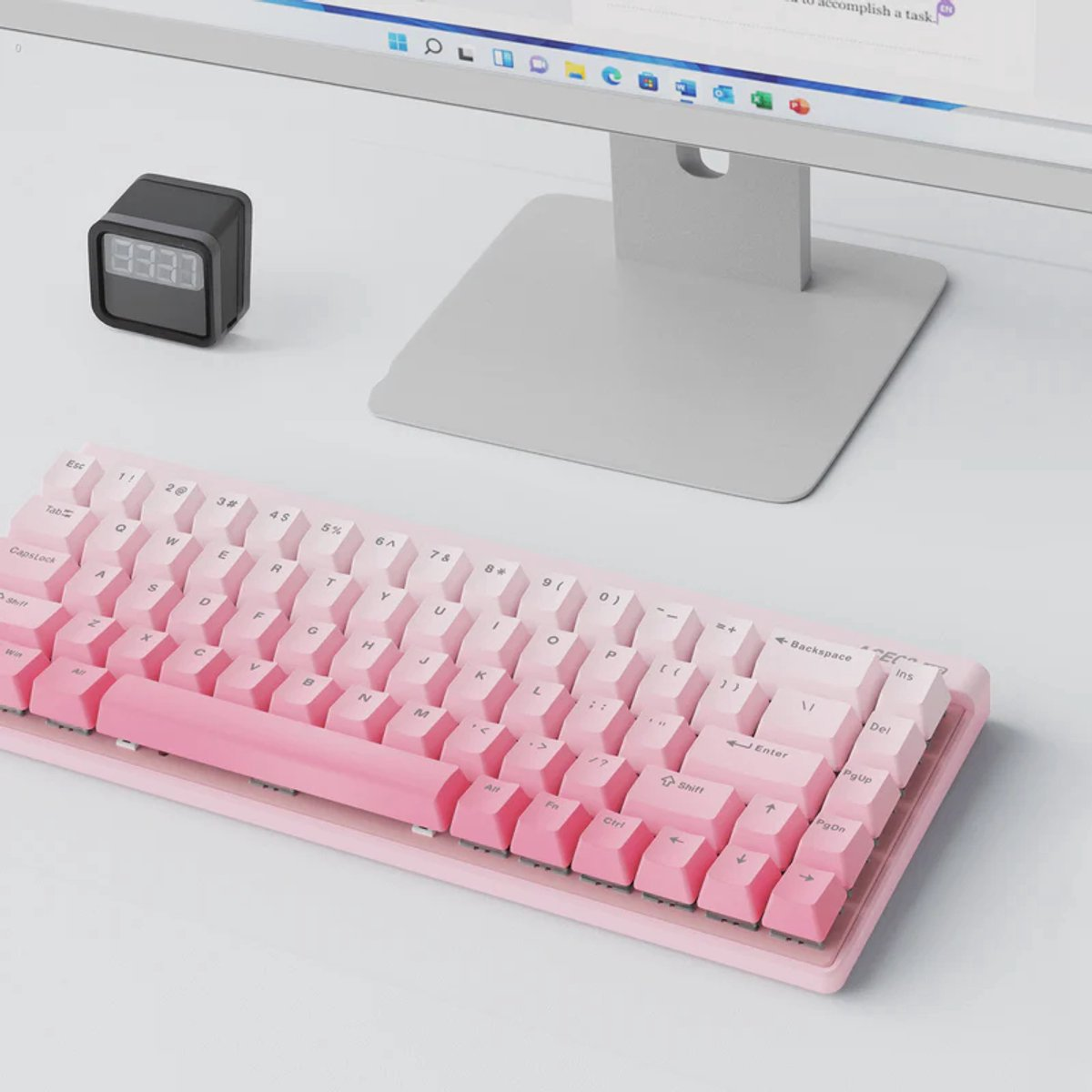 Een roze bureau met toetsenbord, klok en monitor.
