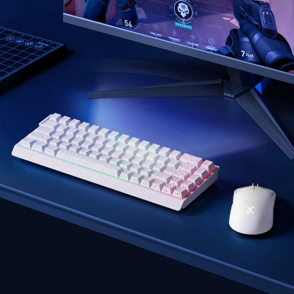 Een wit toetsenbord en muis liggen op een blauw bureau voor een computermonitor.
