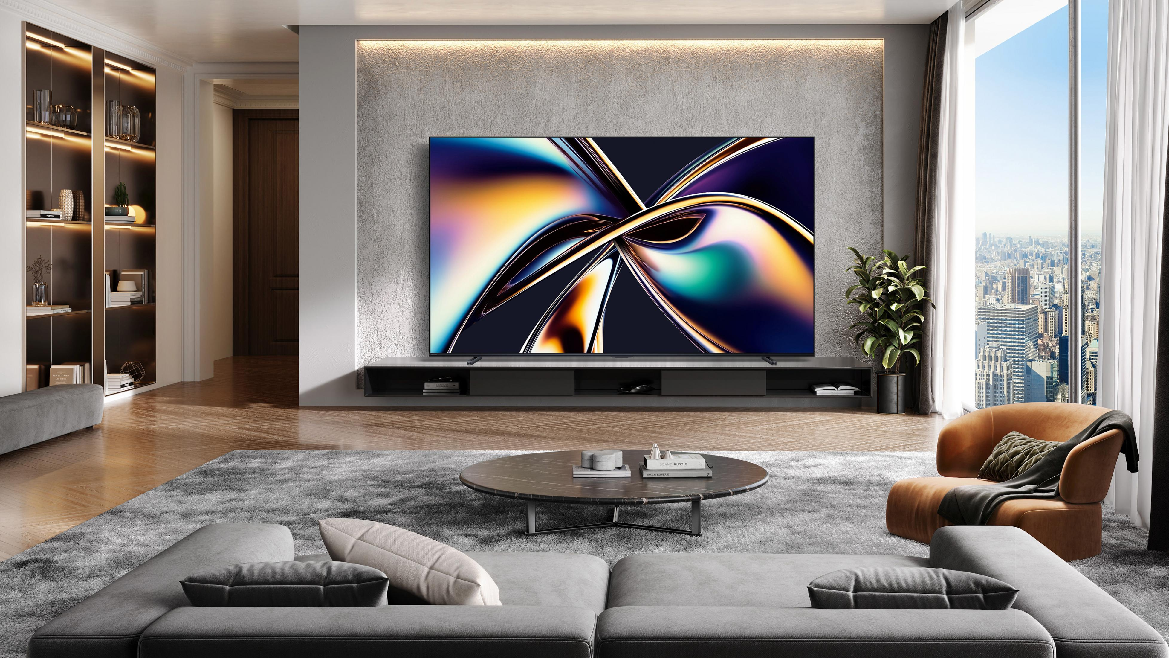 Sala de estar moderna con TV grande, sofá, sillón y vista a la ciudad.