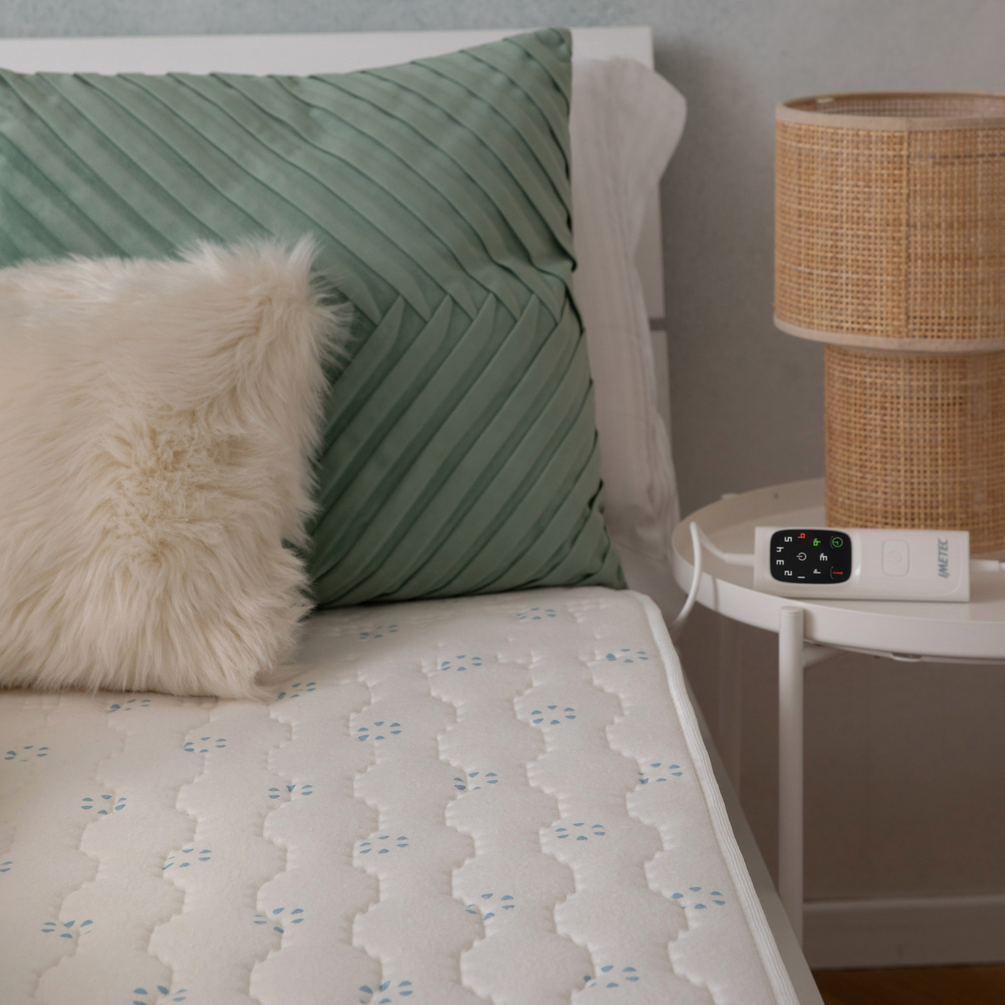 Un controller bianco poggia su un comodino accanto a un letto con cuscini.