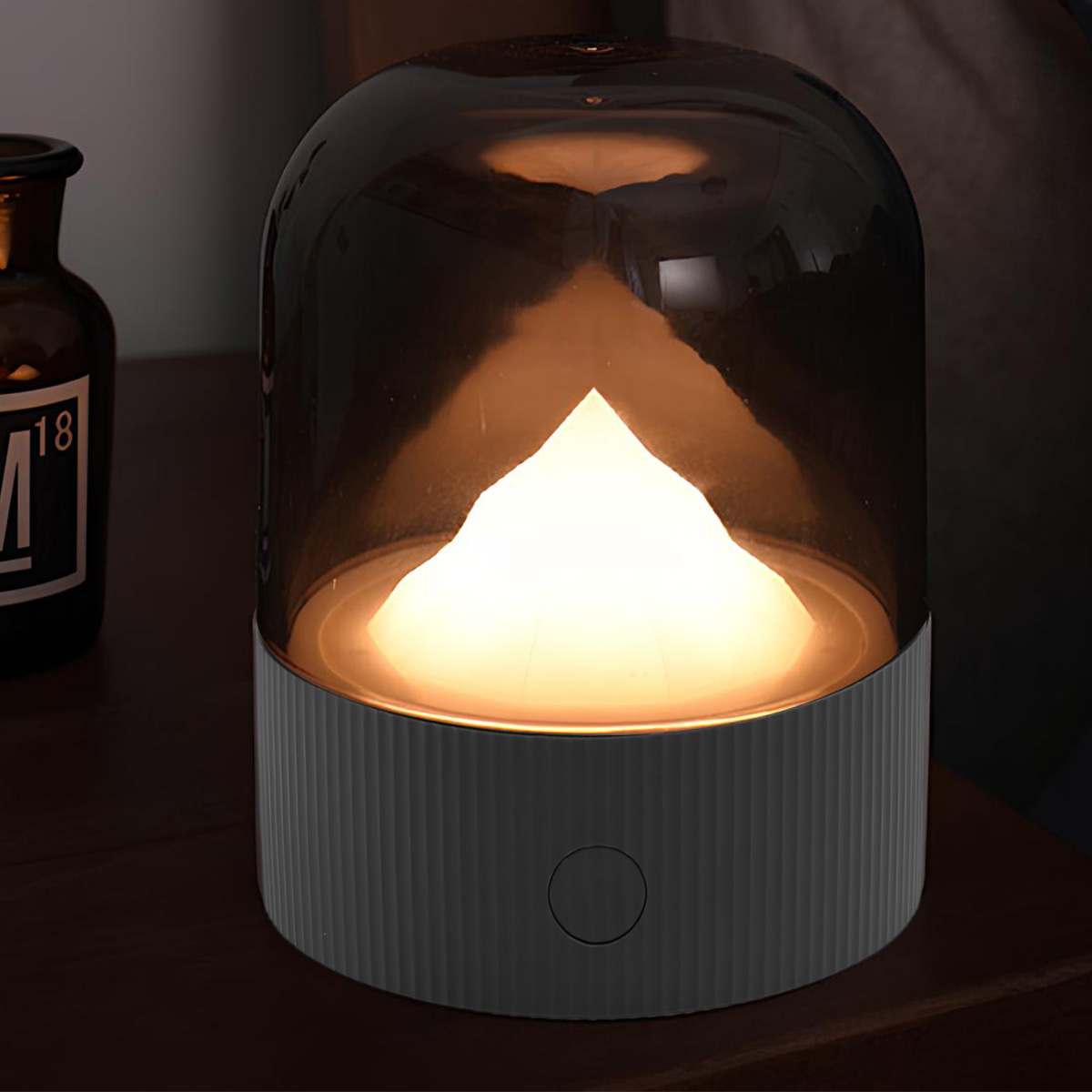 Eine beleuchtete Lampe mit einem grauen Sockel und einem Rauchglas-Schirm.