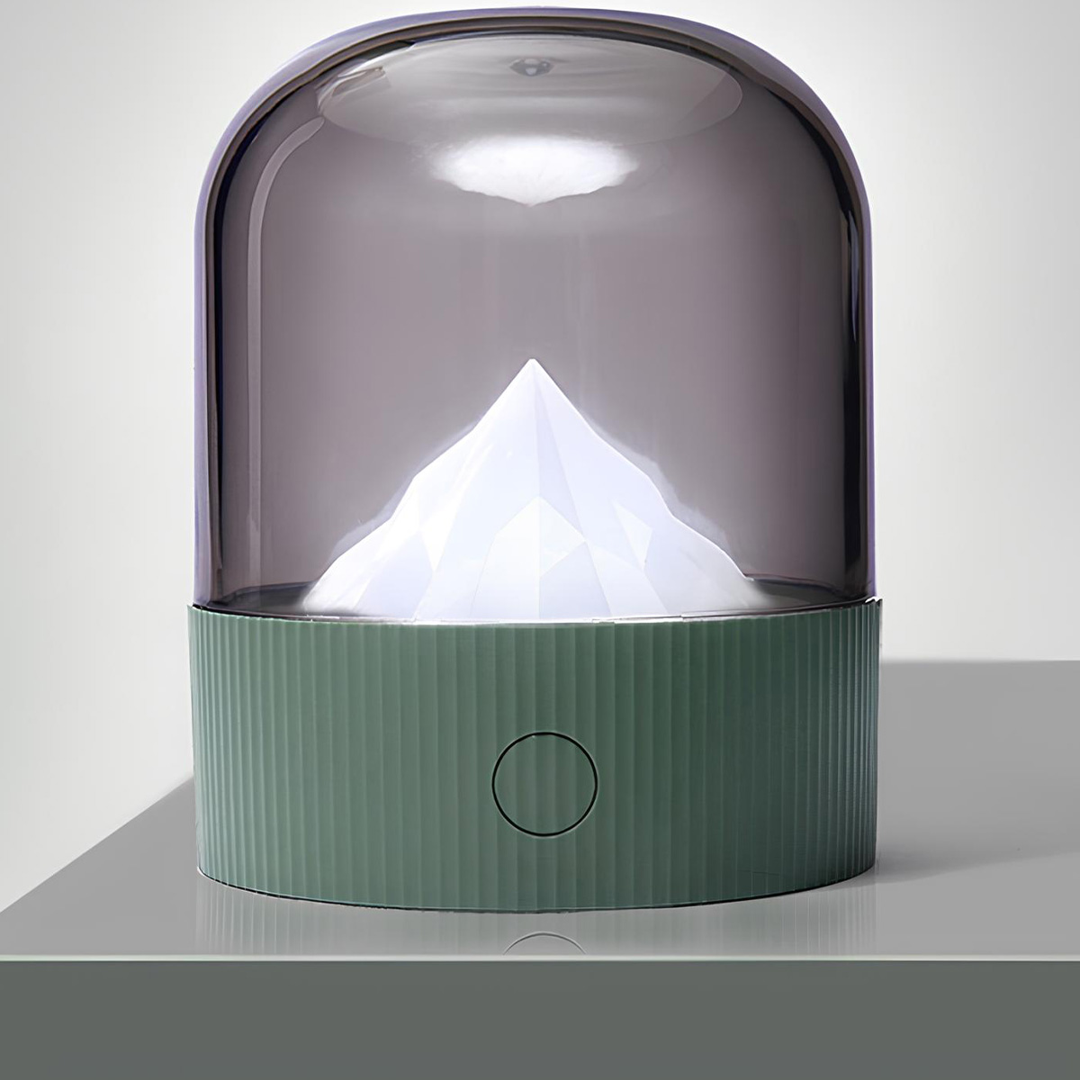 Grüne Lampe mit Bergmotiv unter dunklem Glas und einem Kreis-Schalter.