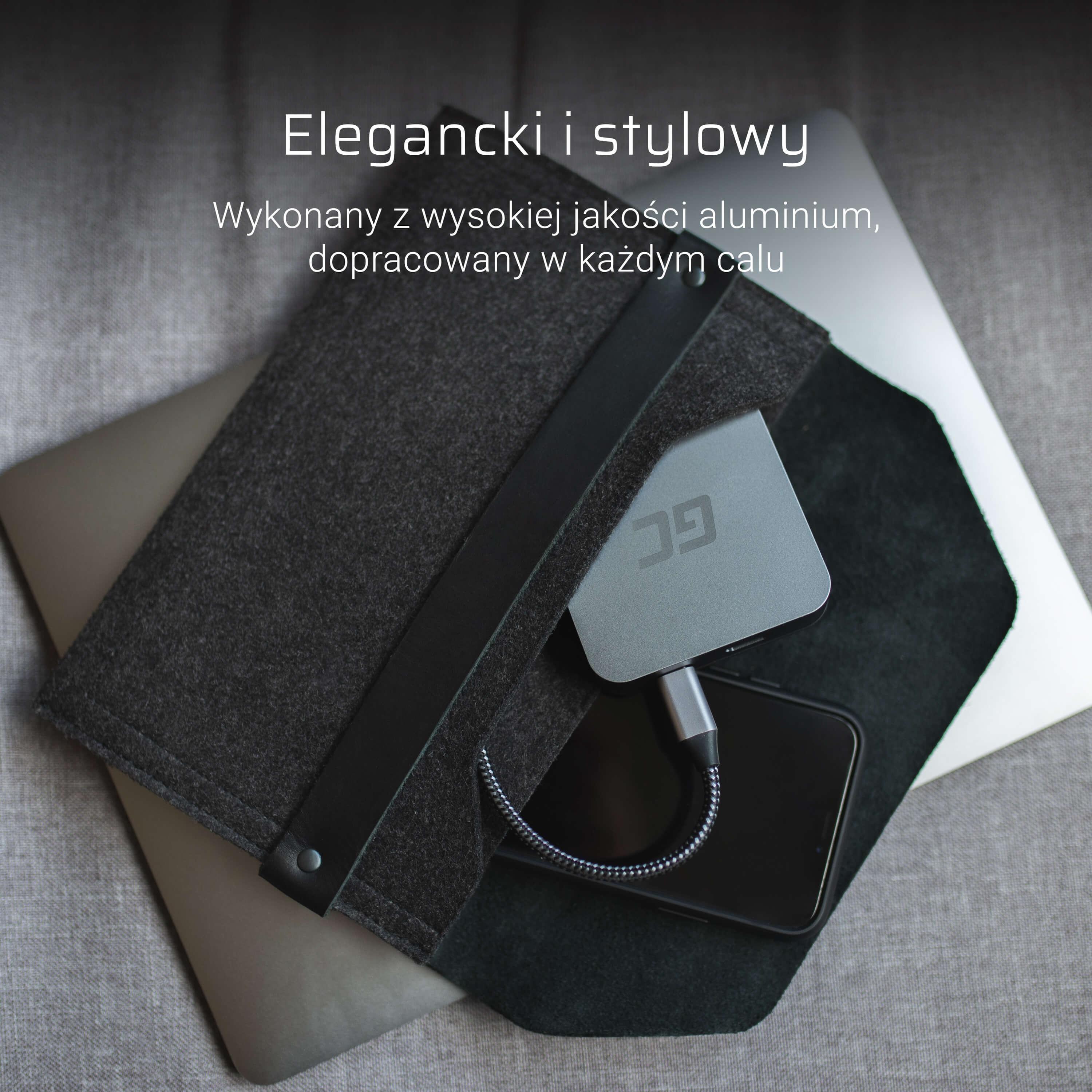 Hub USB grigio in alluminio con cavo, accanto a uno smartphone e laptop.