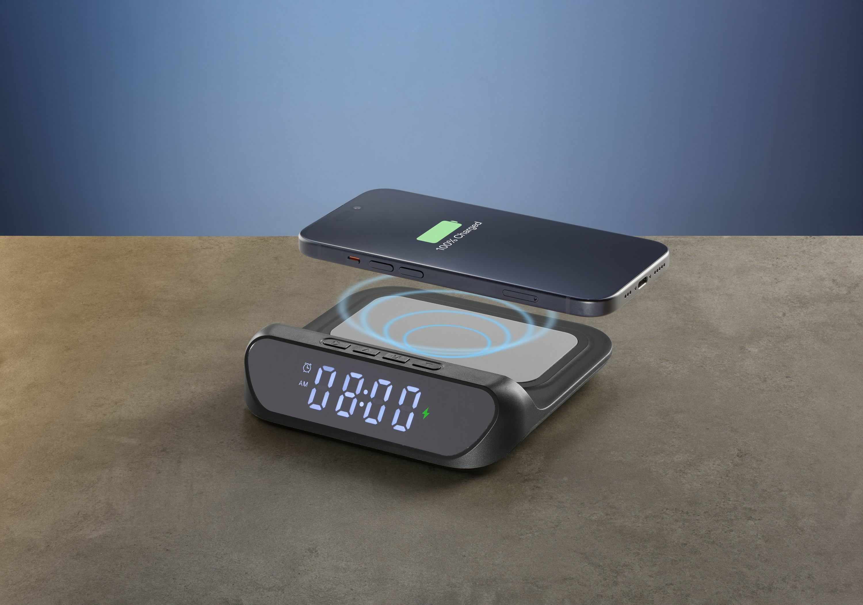 Un smartphone se carga inalámbricamente en un reloj digital negro con indicadores azules.