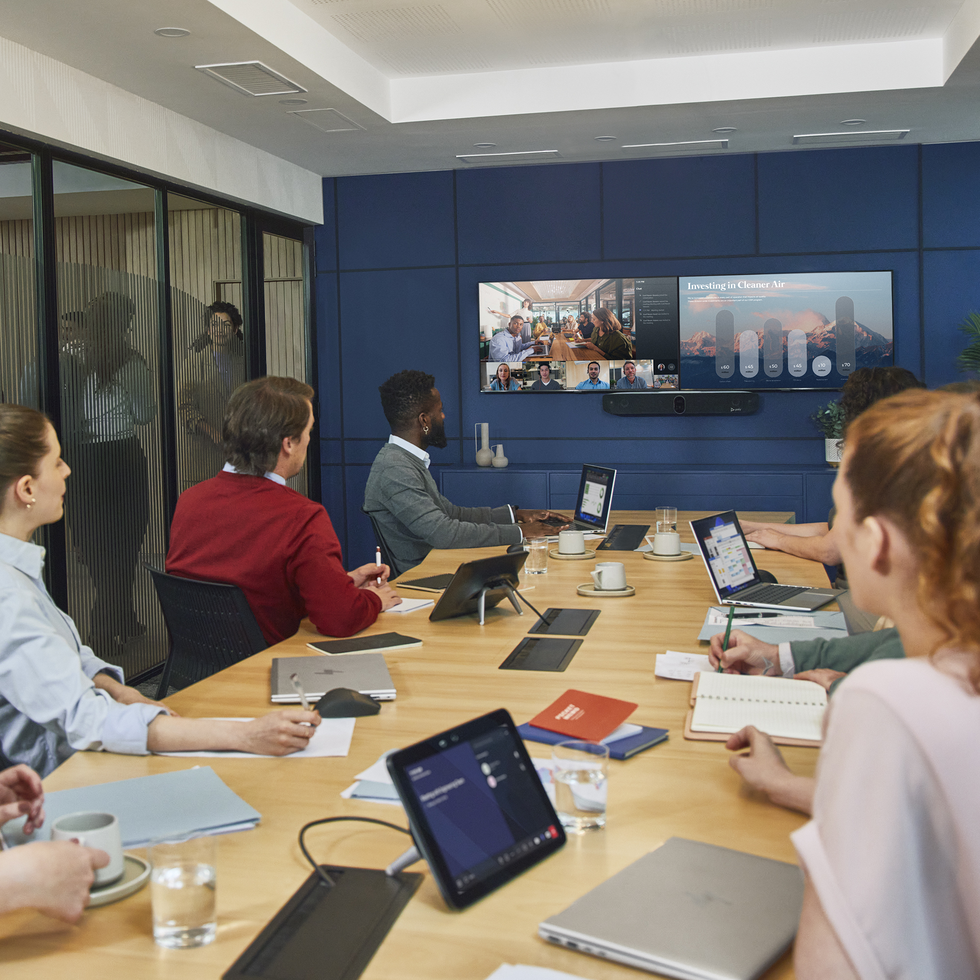 Persone in una sala riunioni con videoconferenza sullo schermo.