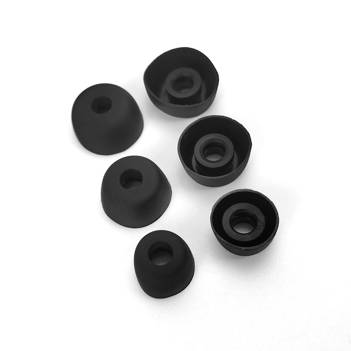 Sześć czarnych końcówek do słuchawek na białym tle, niektóre pionowo, inne odwrócone.