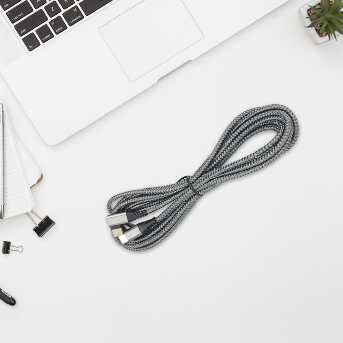 Graues USB-Kabel mit zwei Anschlüssen liegt neben einem Laptop.